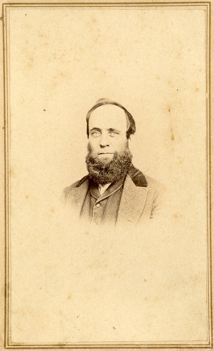 Vintage sepia-toned portrait of a bearded man with a suit, framed photograph.