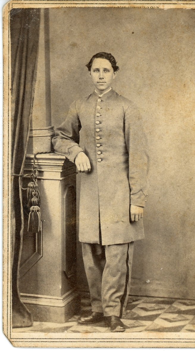 Vintage photograph of a man in a military uniform standing next to a column with drapery.
