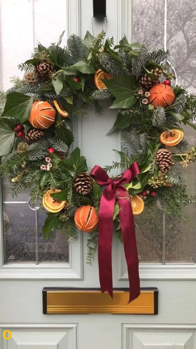 a christmas wreath made with fir and spruce, decorated with pine cones and dried oranges