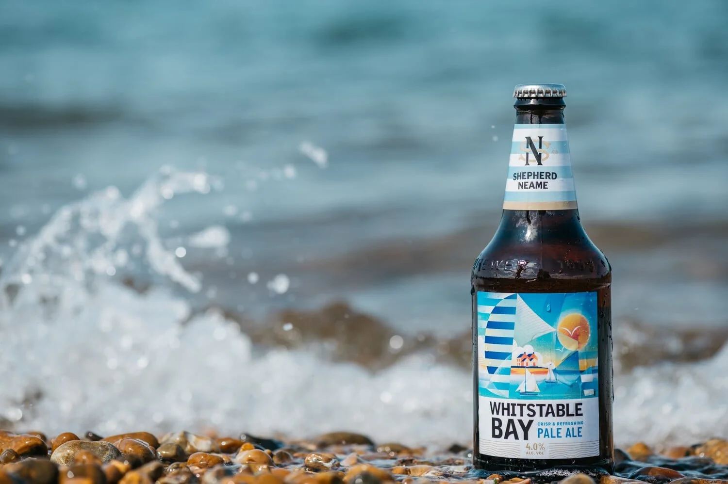 Shelf | fulfilment for drinks brands - A bottle of Whitstable Bay Pale Ale on Whitstable beach with sea waves in the background