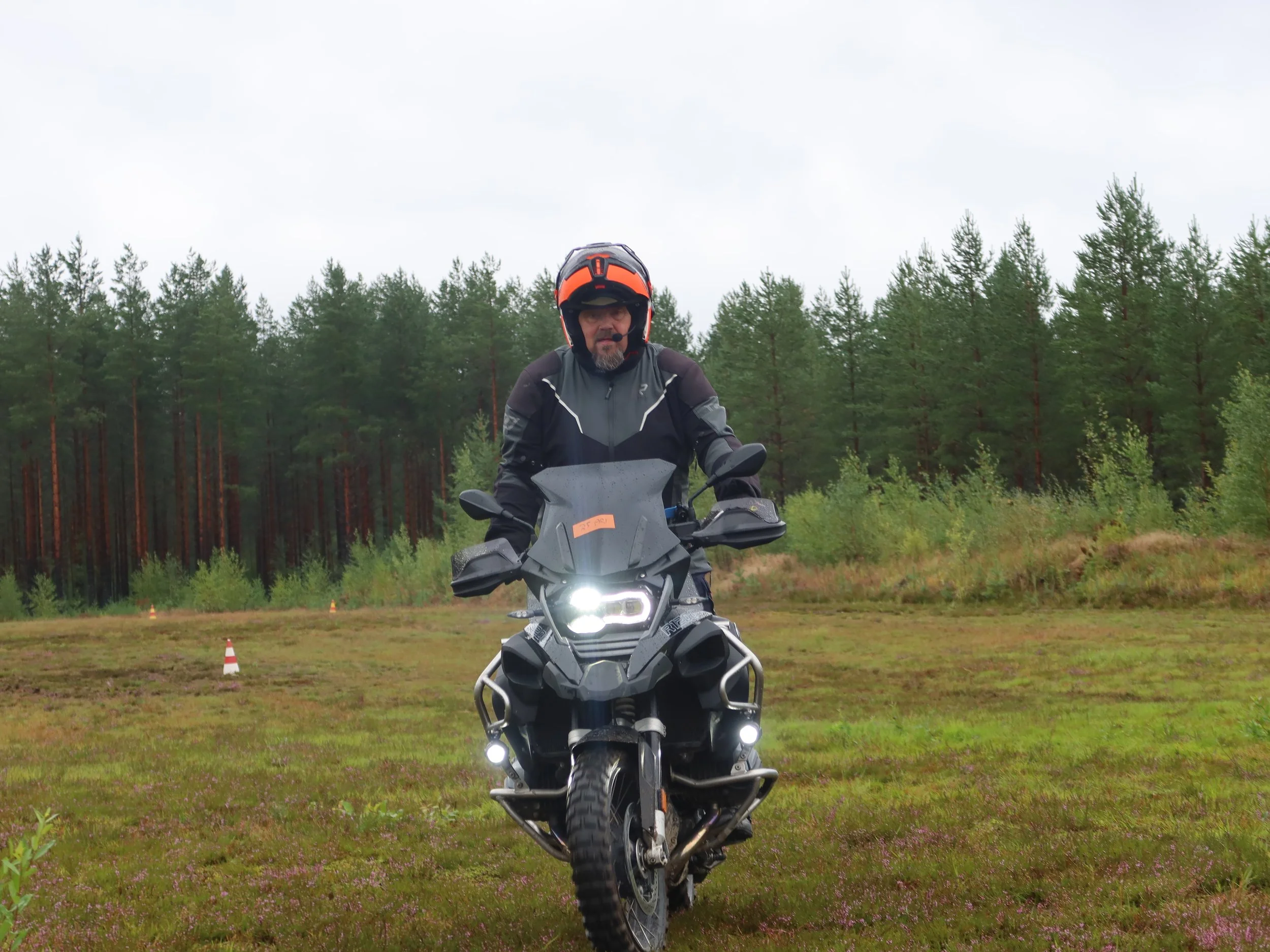 Mies ajamassa reitillä hänen matkapyörällään, taustalla metsä ja pilvinen taivas.