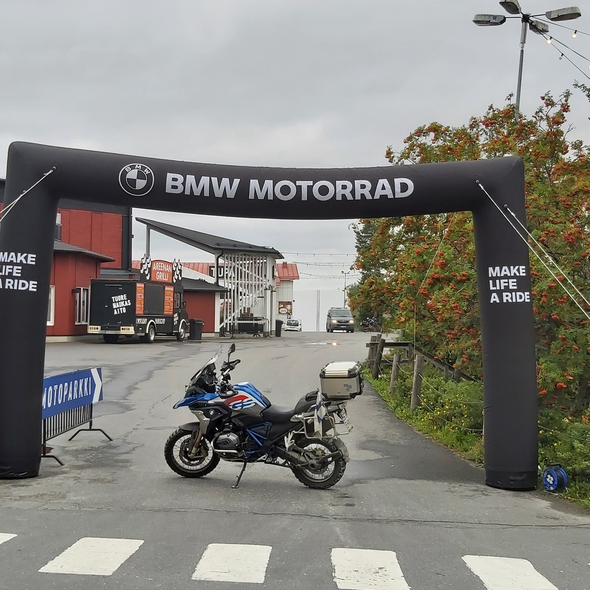 Tummansininen BMW GS -motocykli pysäköitynä BMW Motorsportin pystytyksen edessä, jonka yläosassa lukee "BMW MOTORRAD" ja joka on pystyssä puhallettava tapahtuma-areena.