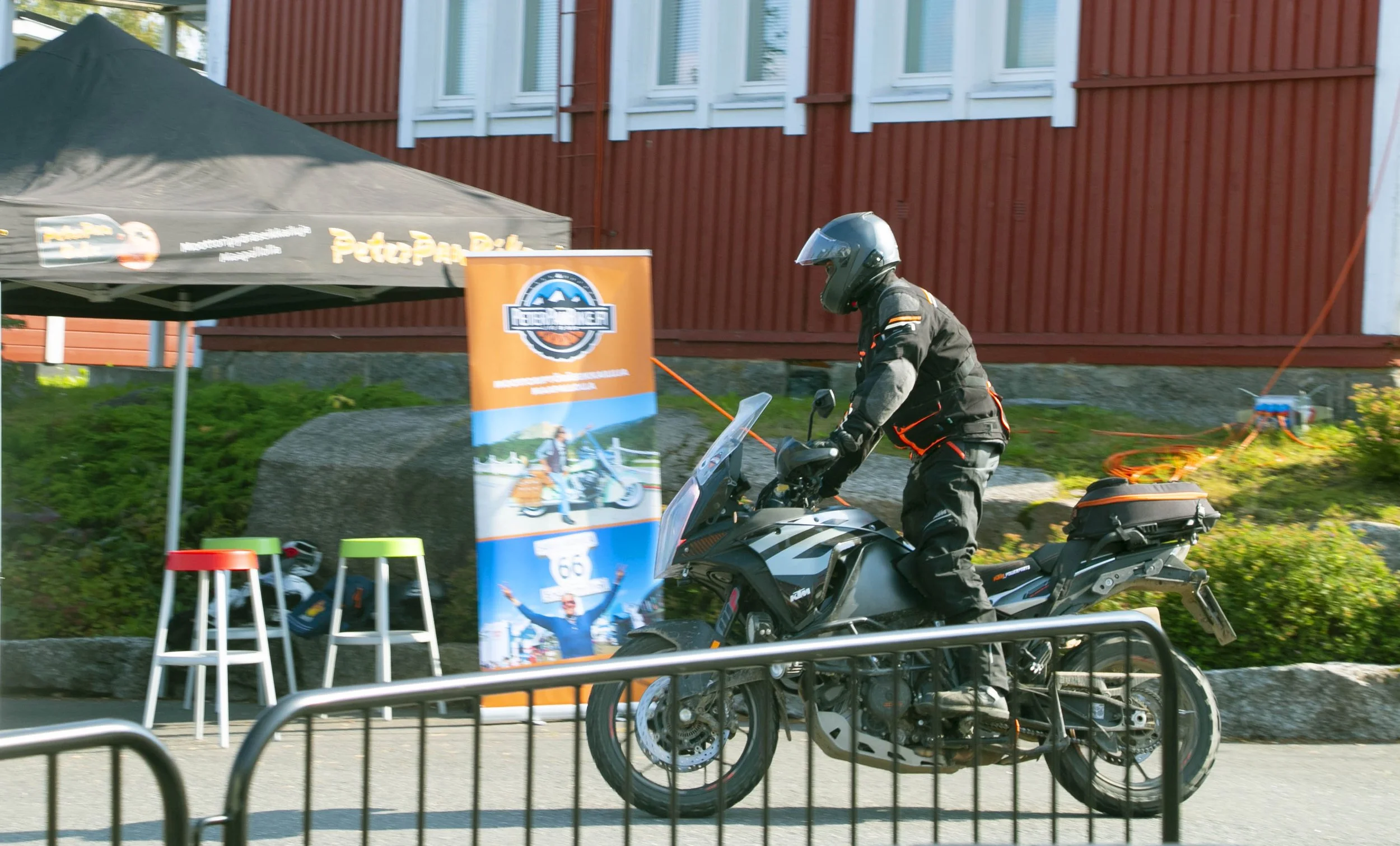 Miehellä on suojavisiiri ja takki, hän istuu motocross-moottoripyörällä ja kiinnittää sen reppuun ladattavaa akkua