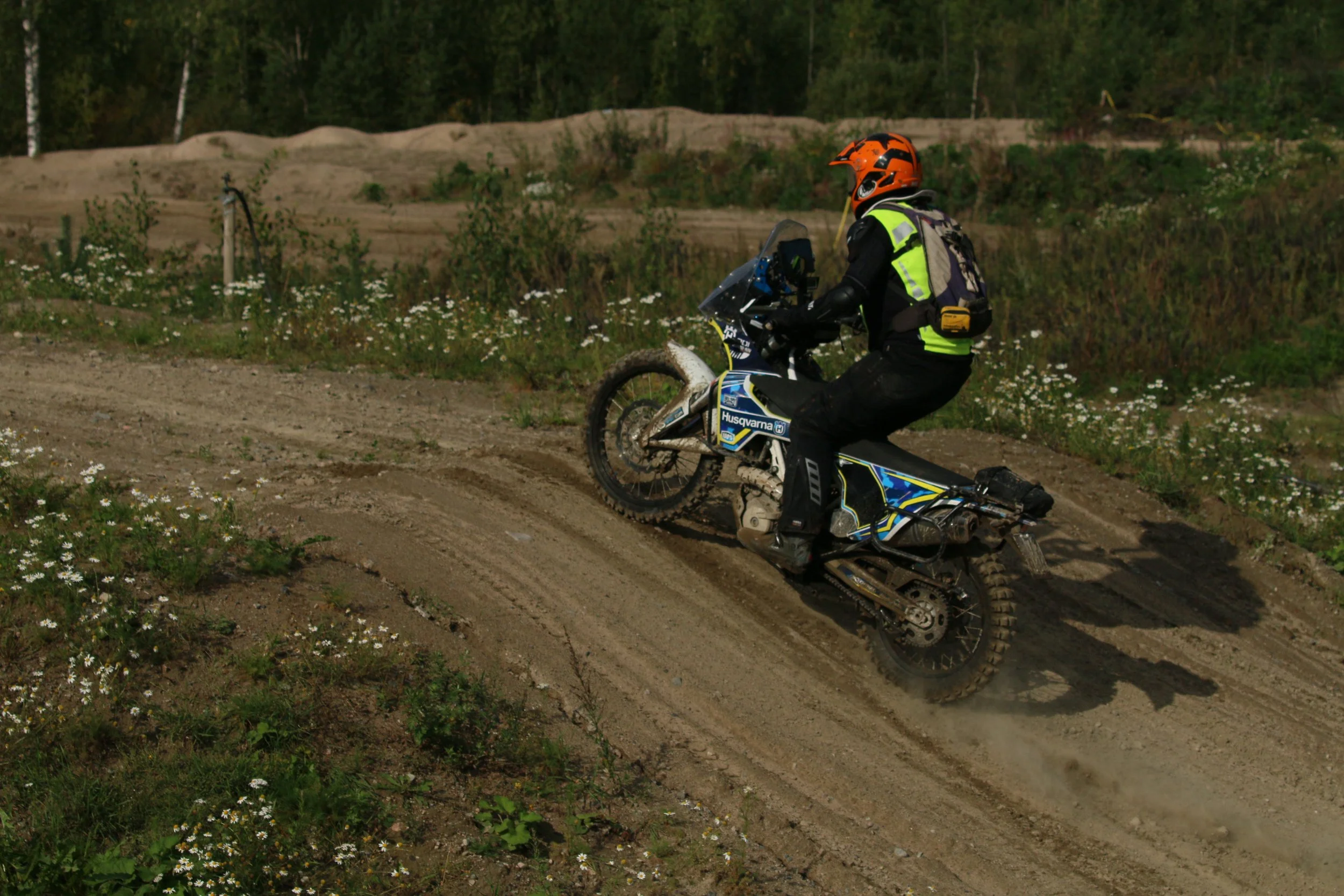 Moottoripyöräilijä ajamassa maastossa, peittäen kypärän ja varusteet