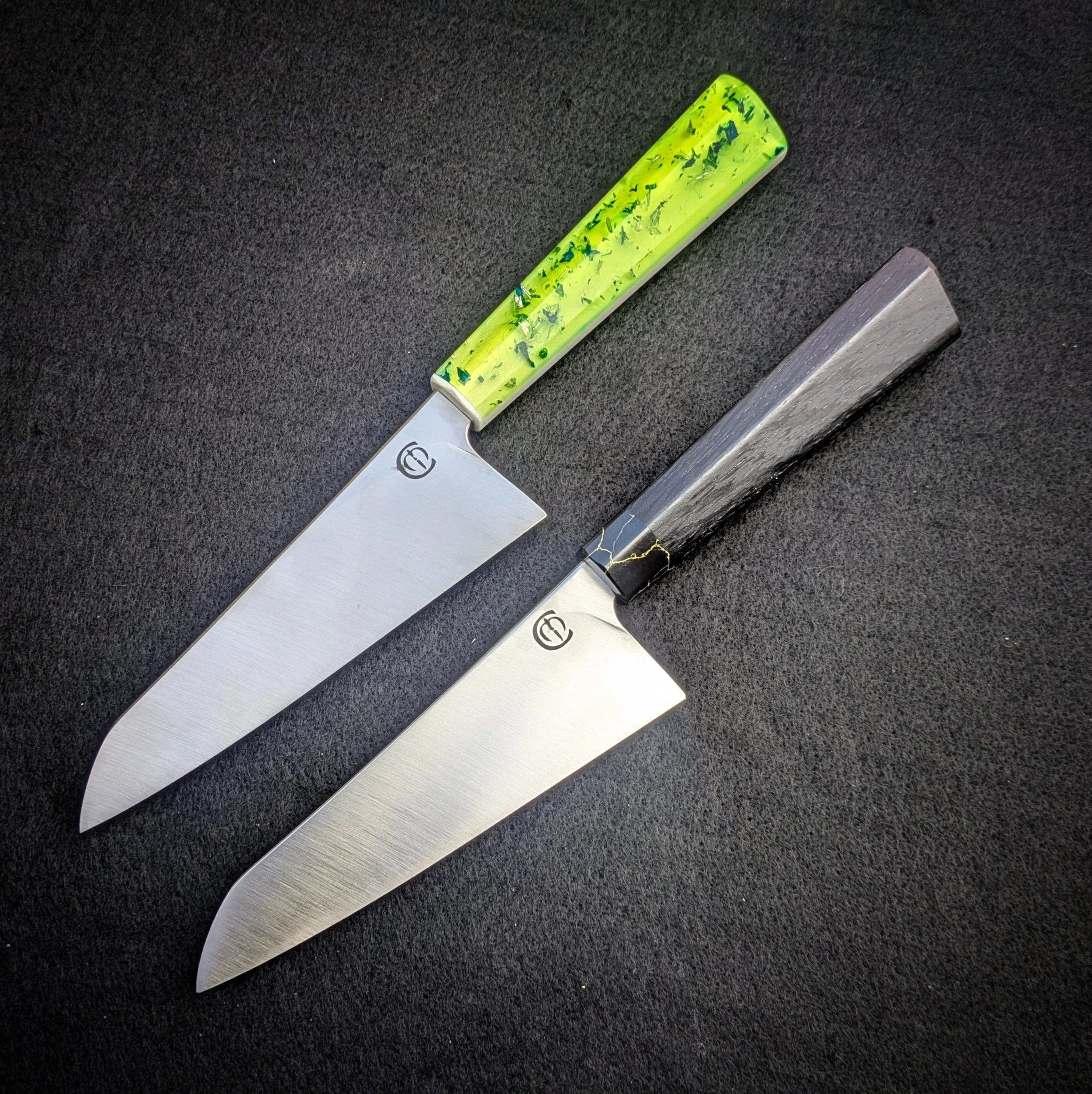 Close-up view of two kitchen knives with different handles on a black countertop.