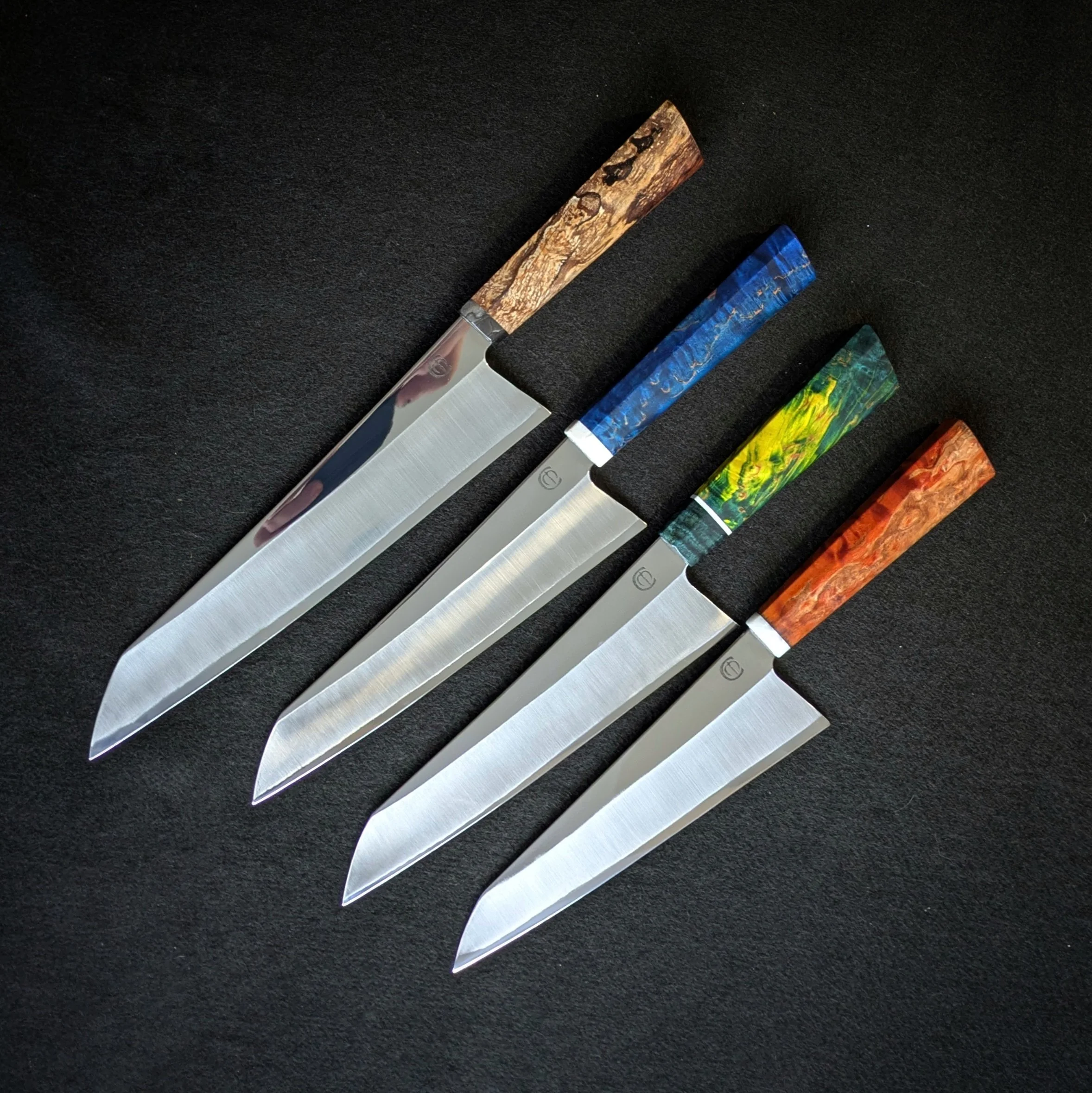 Close-up view of a collection of knives with decorative handles on a black surface.