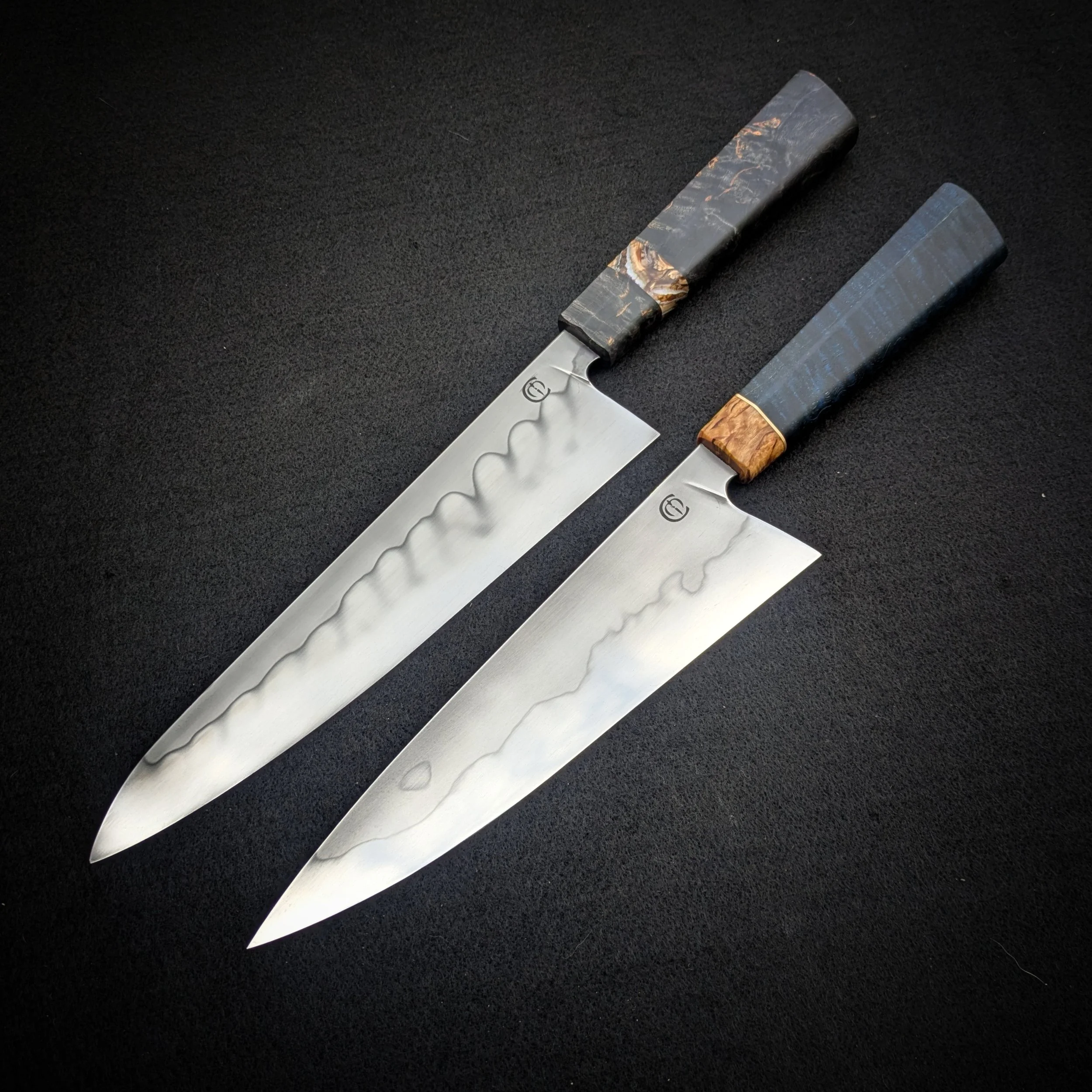 Two kitchen knives with patterned handles on a black surface.