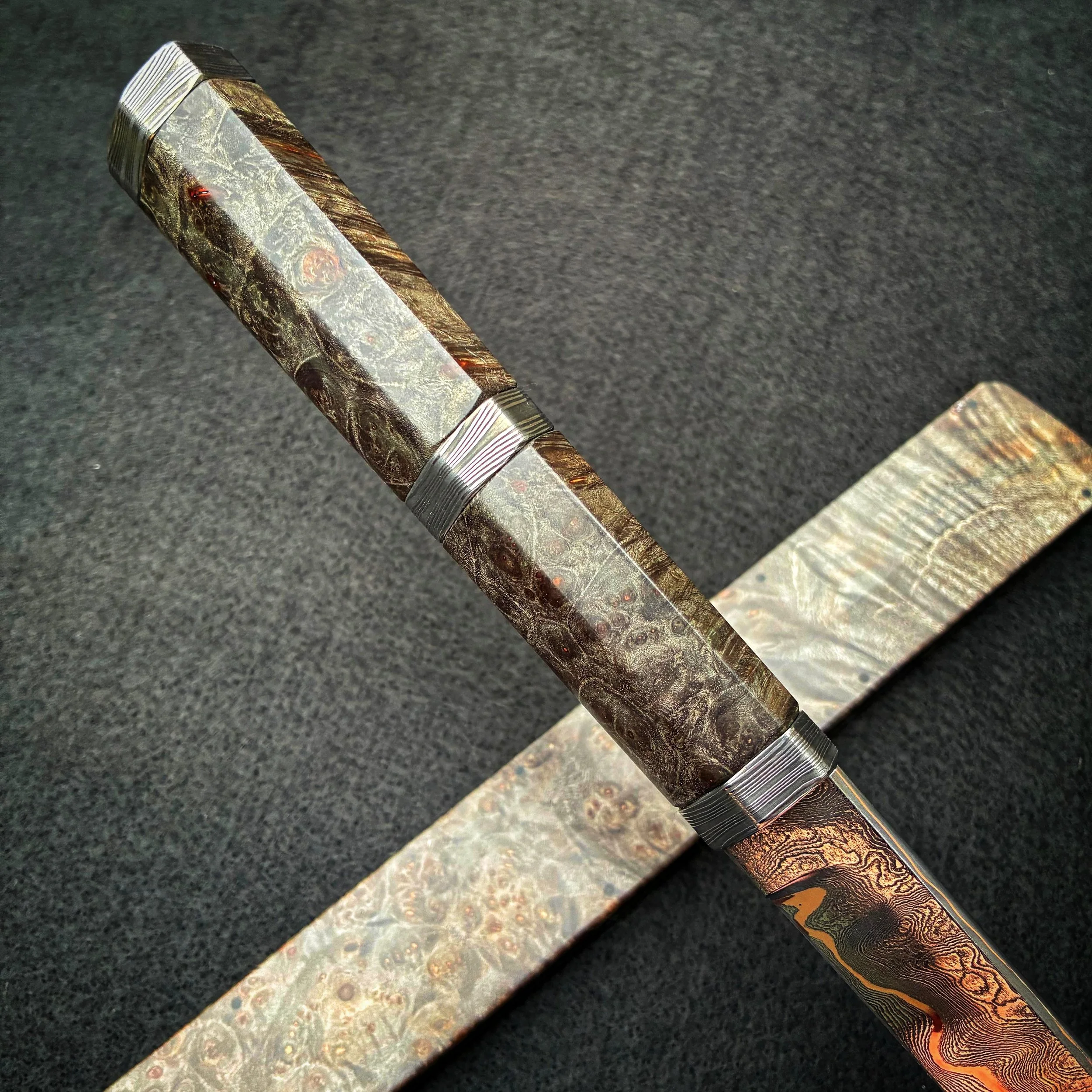 Close-up of a decorated handle and blade of a knife with intricate, colorful patterns on the handle.