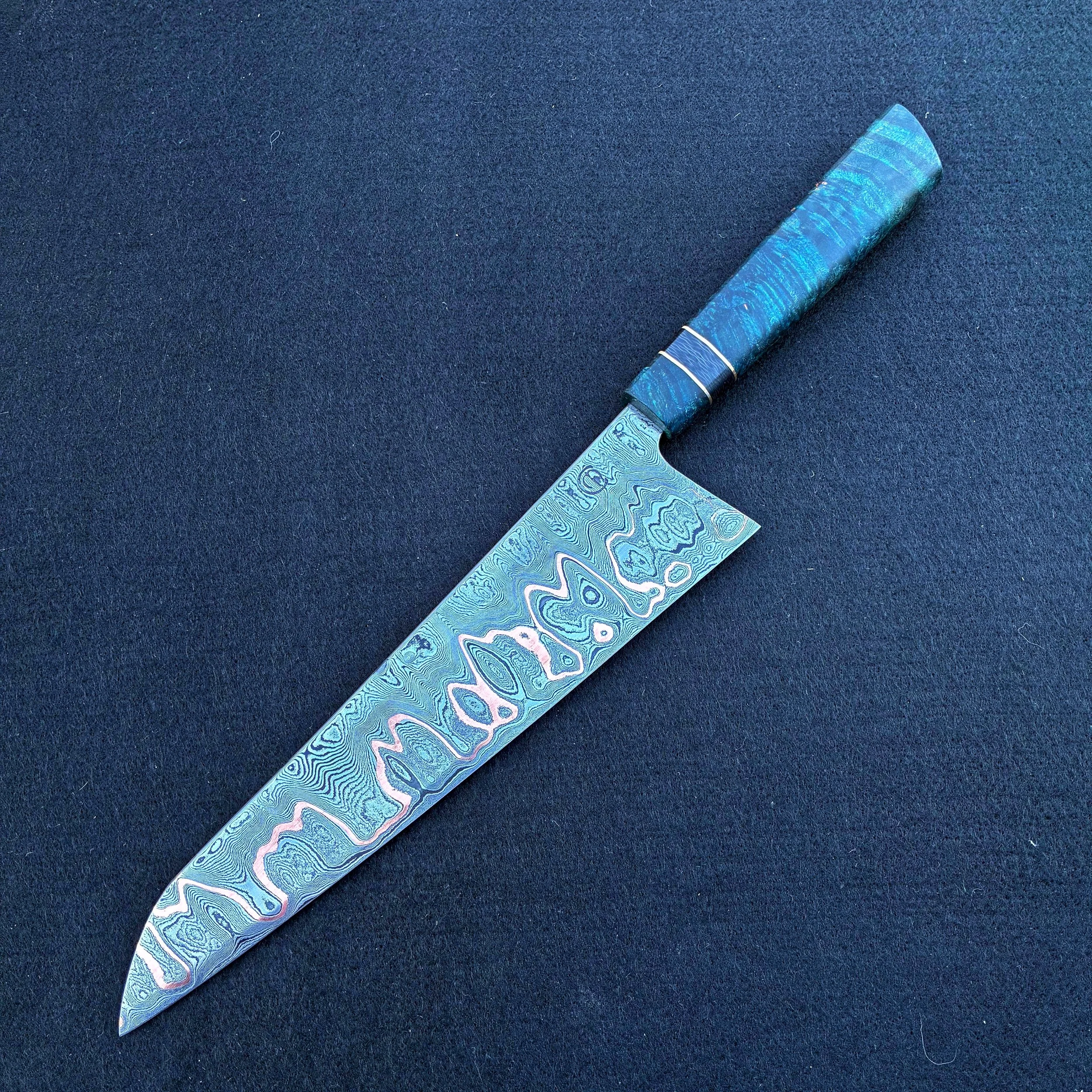A Japanese-style knife with a patterned blade and a matching blue handle, placed on a dark surface.