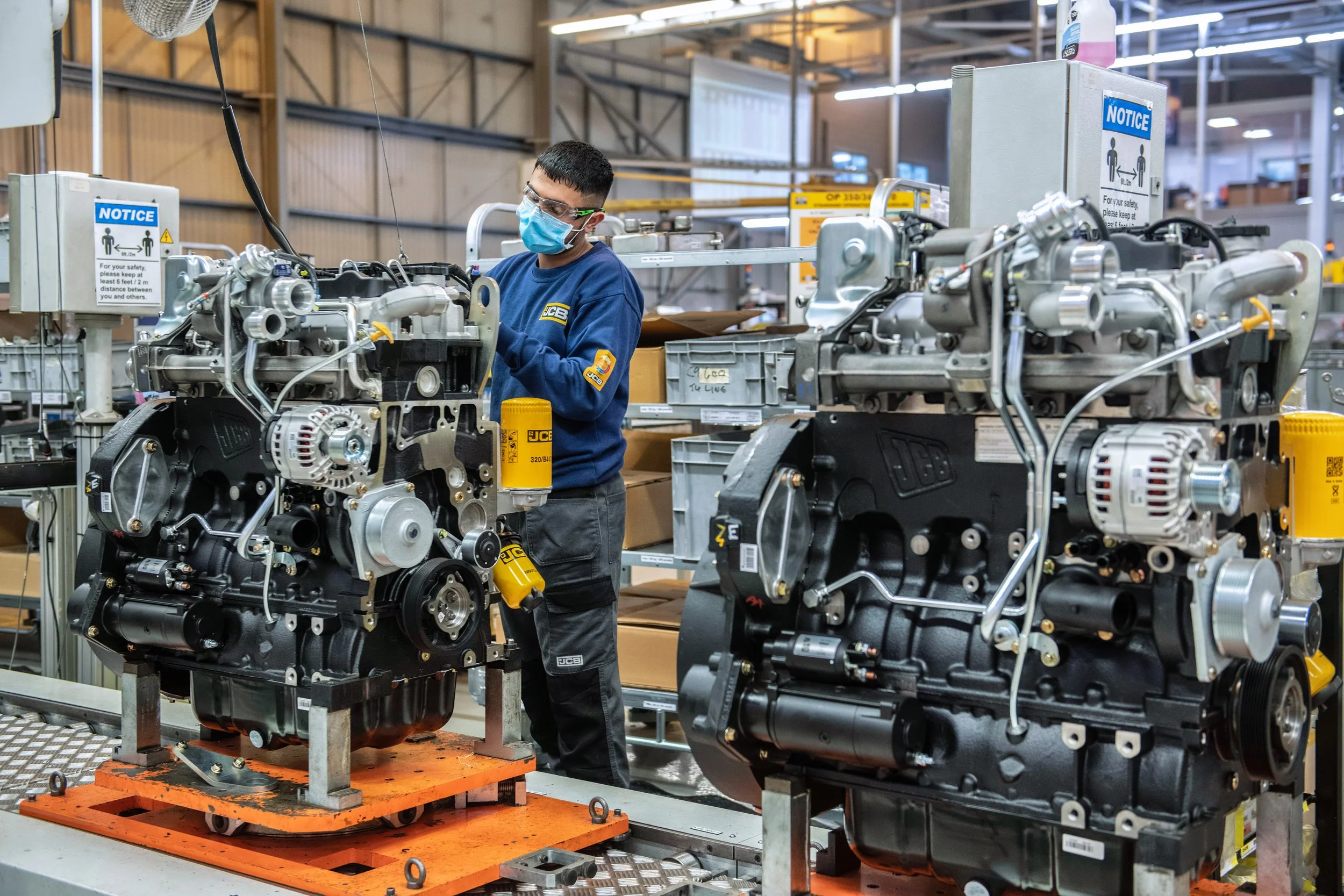 Industrial workers assembling JCB machines on production floor