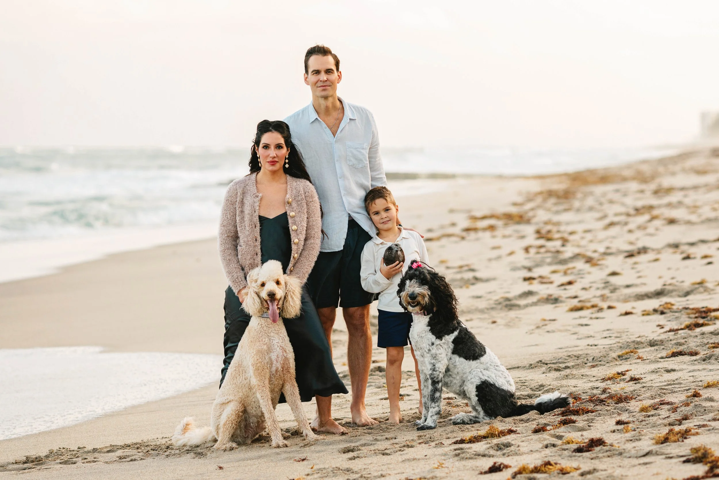 Family with their dogs standing together during a beach photography session in Delray Beach