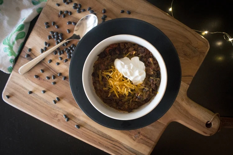 Bowl of poblano and black bean chili topped with cheese and sour cream