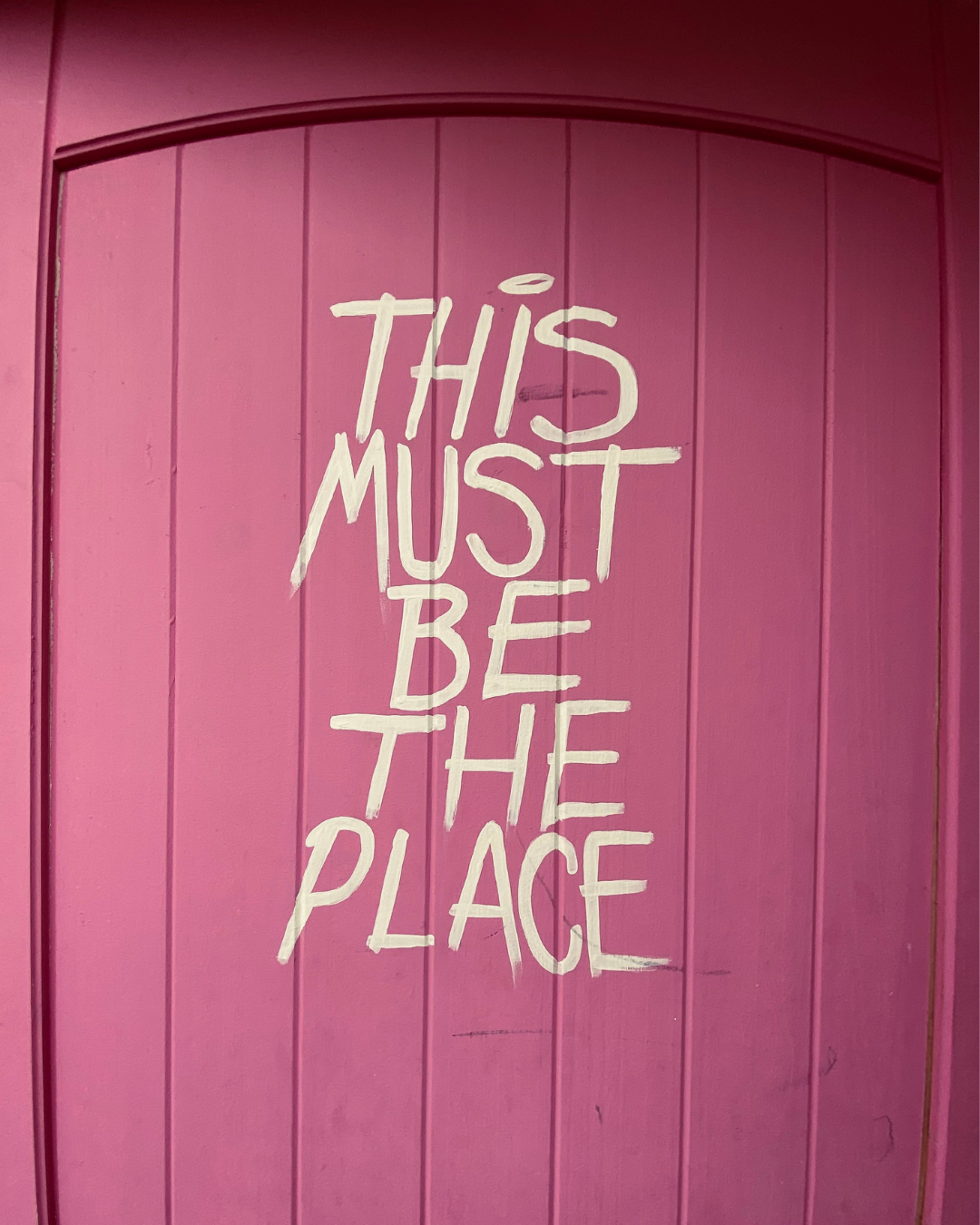 Pink door at wellness event venue that reads "this must be the place"