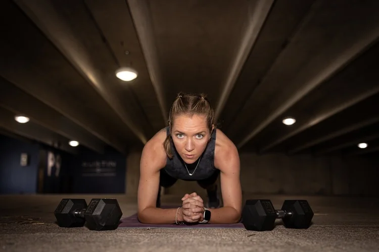 Coach Lisa holding a forearm plank between two dumbbells