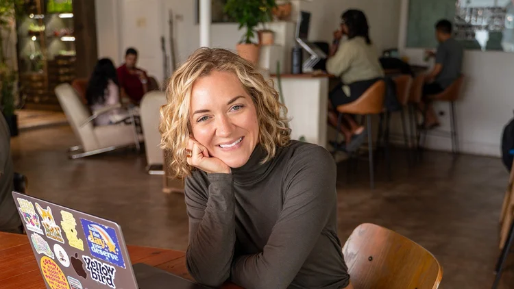 Coach Lisa Wade smiling with her laptop at a coworking table, The Well-Run Business