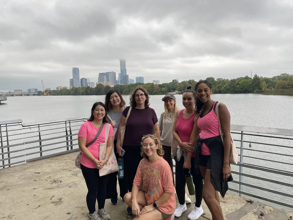 Walk With Your Breasties walkers in pink on the Lady Bird Lake Boardwalk with the downtown Austin skyline behind them