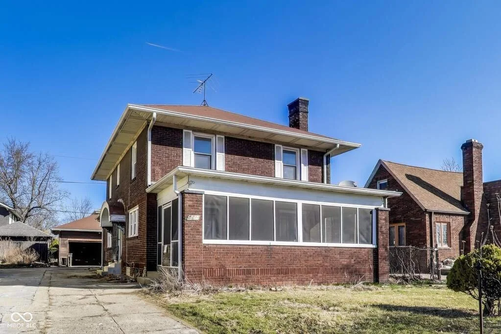 Brick midtown home with historic charm, featuring a sunroom with French doors, stone fireplace, and renovation potential.