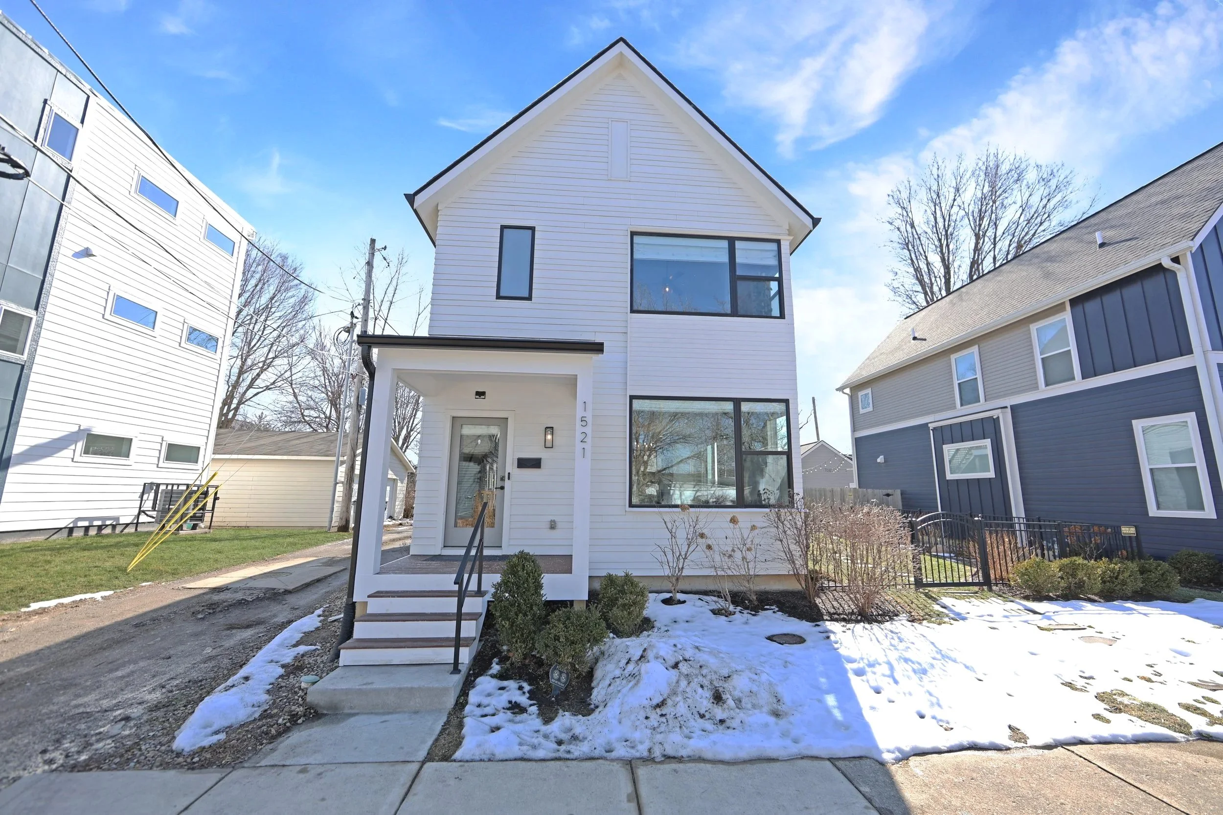 Modern four-bedroom home built in 2020 featuring an open kitchen with large island, finished basement, fenced yard, upper-level deck with wooded and city views, front porch, and attached garage.