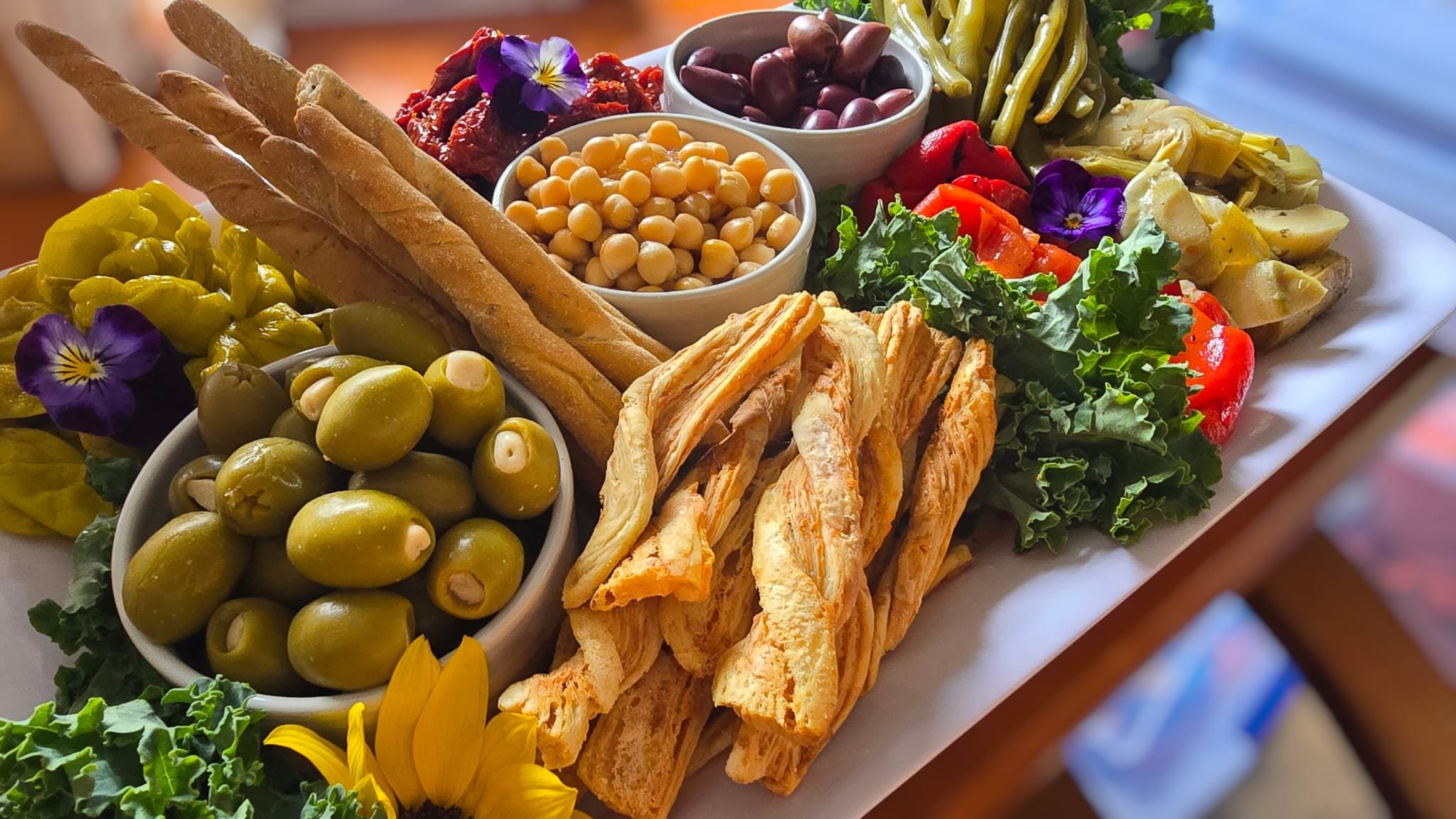 Mediterranean style sharing platter or party platter with chickpeas, olives, sundried tomatoes, breadsticks and cheese stuffed olives.