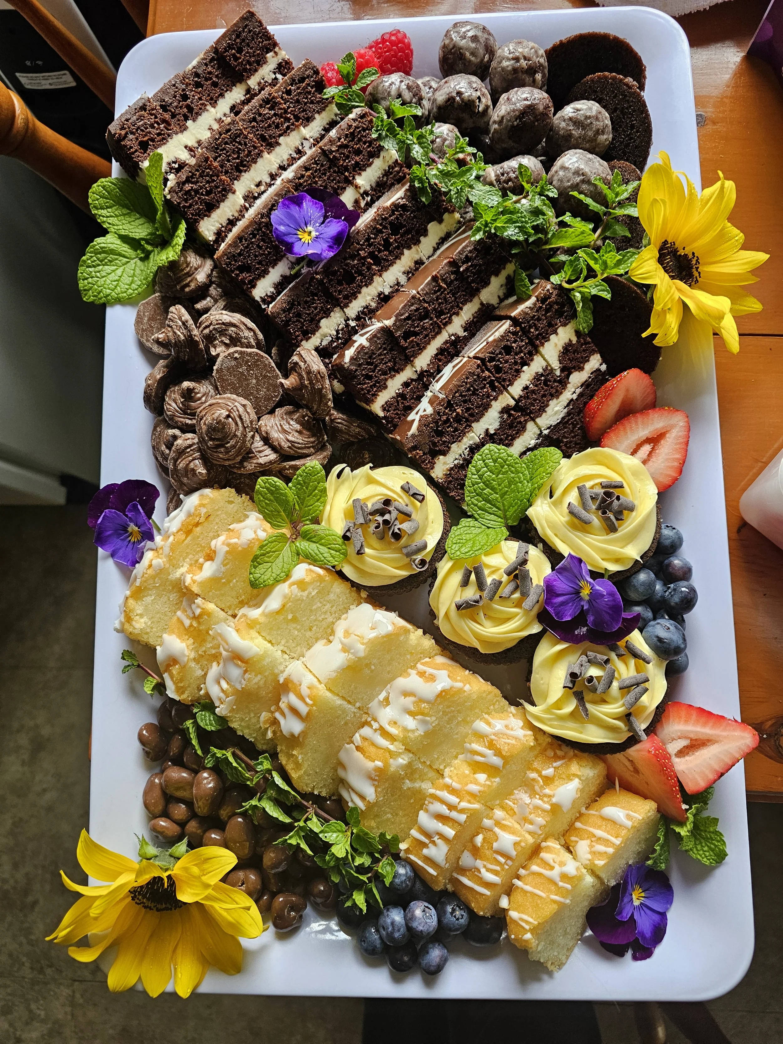 Dessert tray featuring chocolate and lemon cake, as well as cupcakes and bon bons