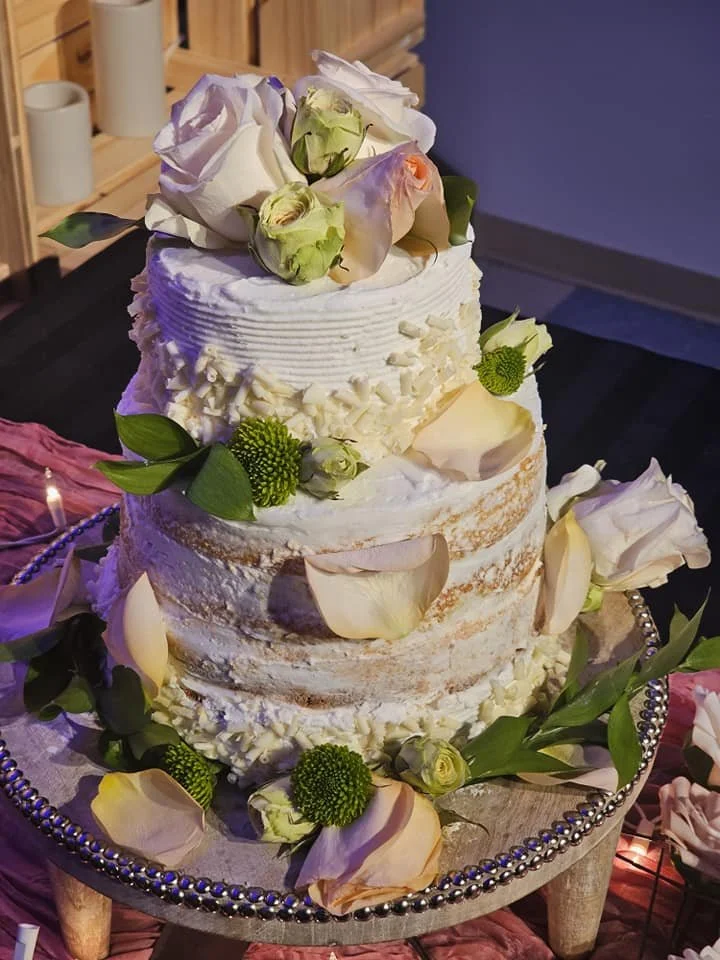 Multi-tiered cake with vanilla frosting and decorated with rose petals