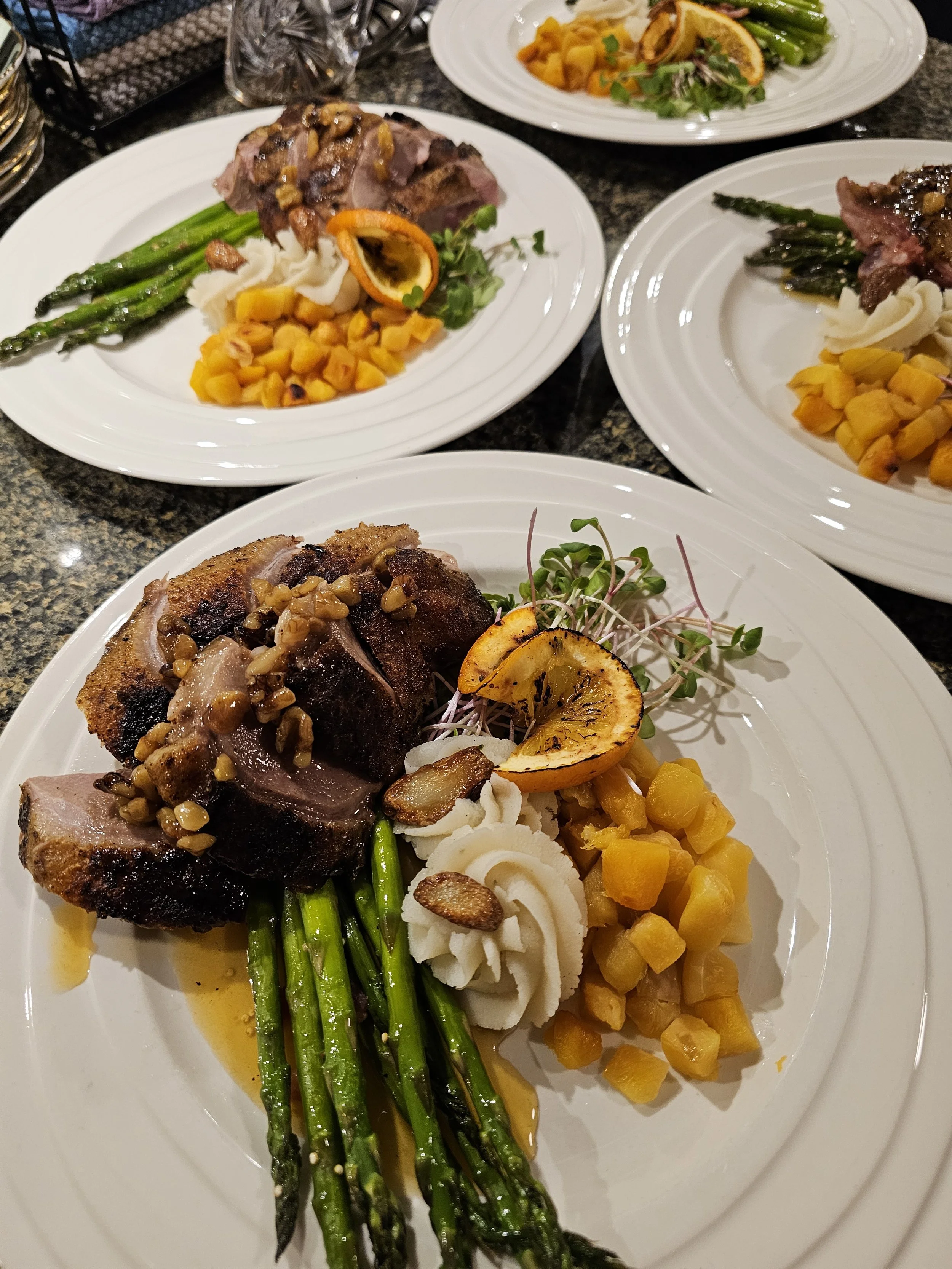 Close up photo of plated dinner of roast pork, asparagus, yams and a swirl of mashed potatoes