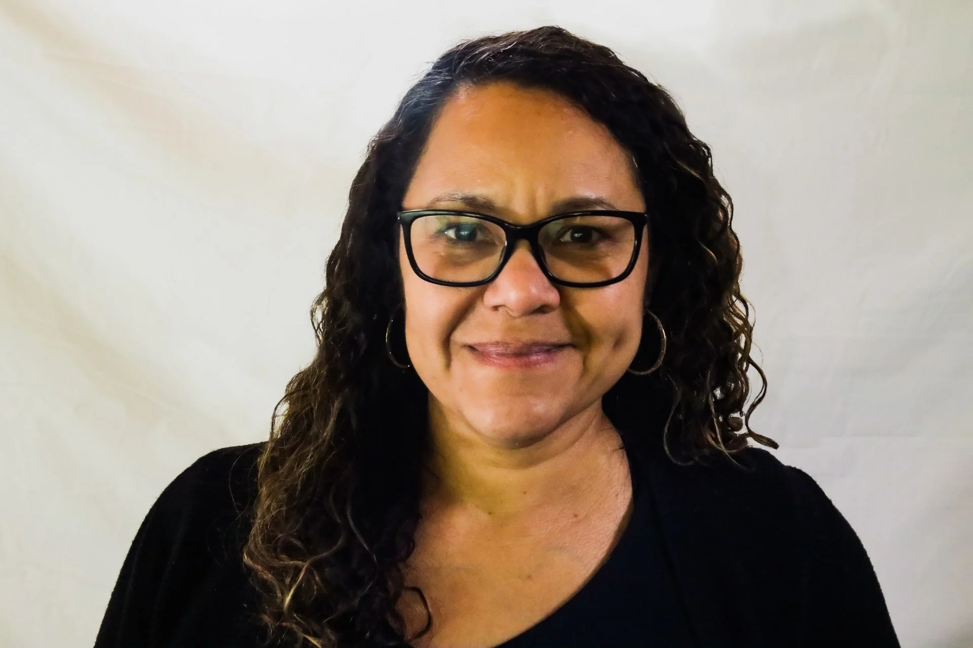 Woman in glasses and long curly hair smiles