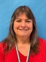 A woman with long light brown hair and bangs wears a red shirt.