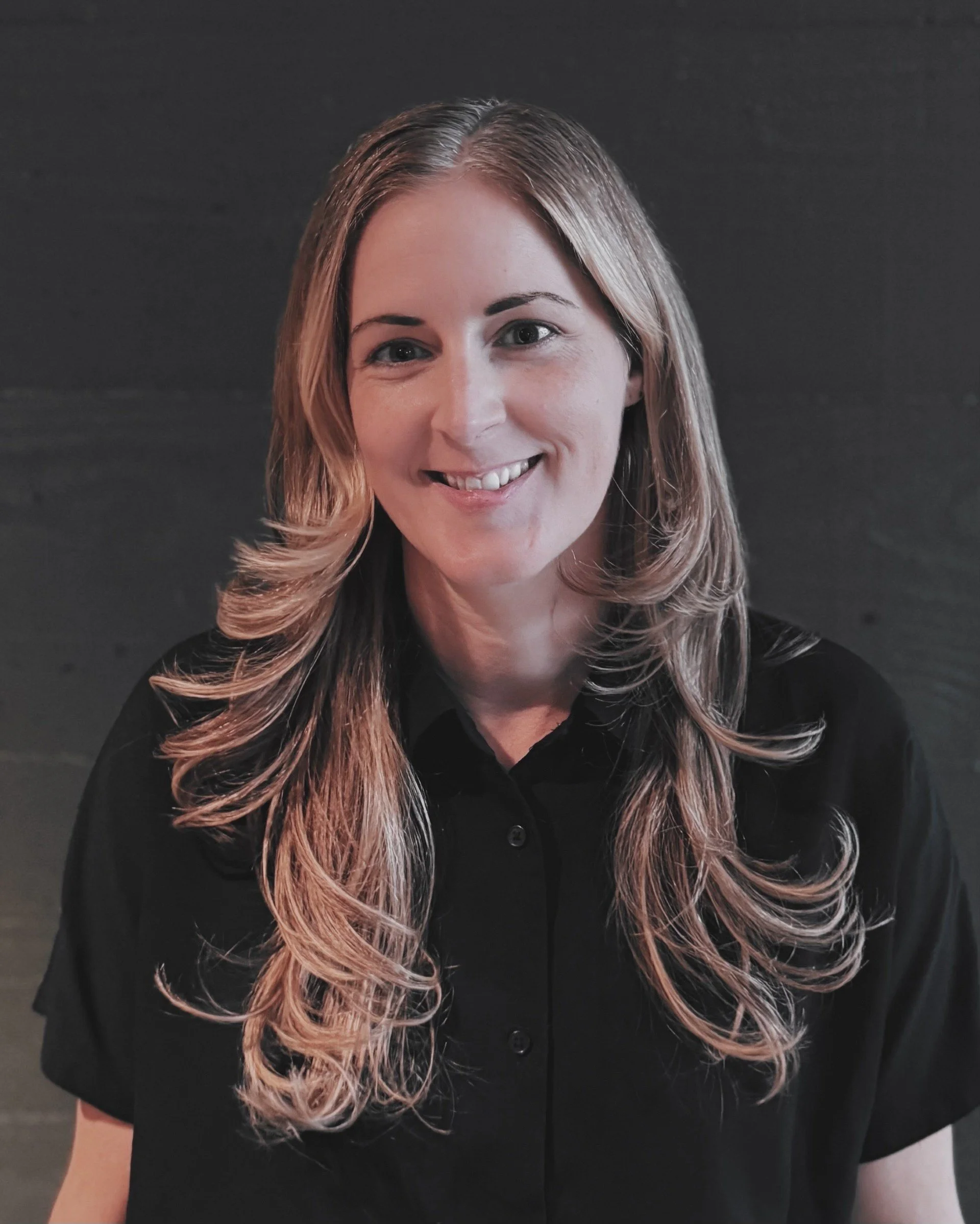 a smiling woman with long, blonde hair, wearing a black shirt