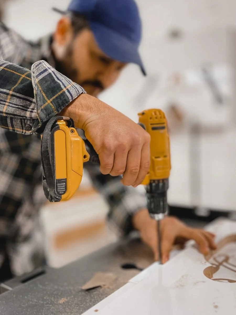 Carpenter using a drill while completing precision wood work