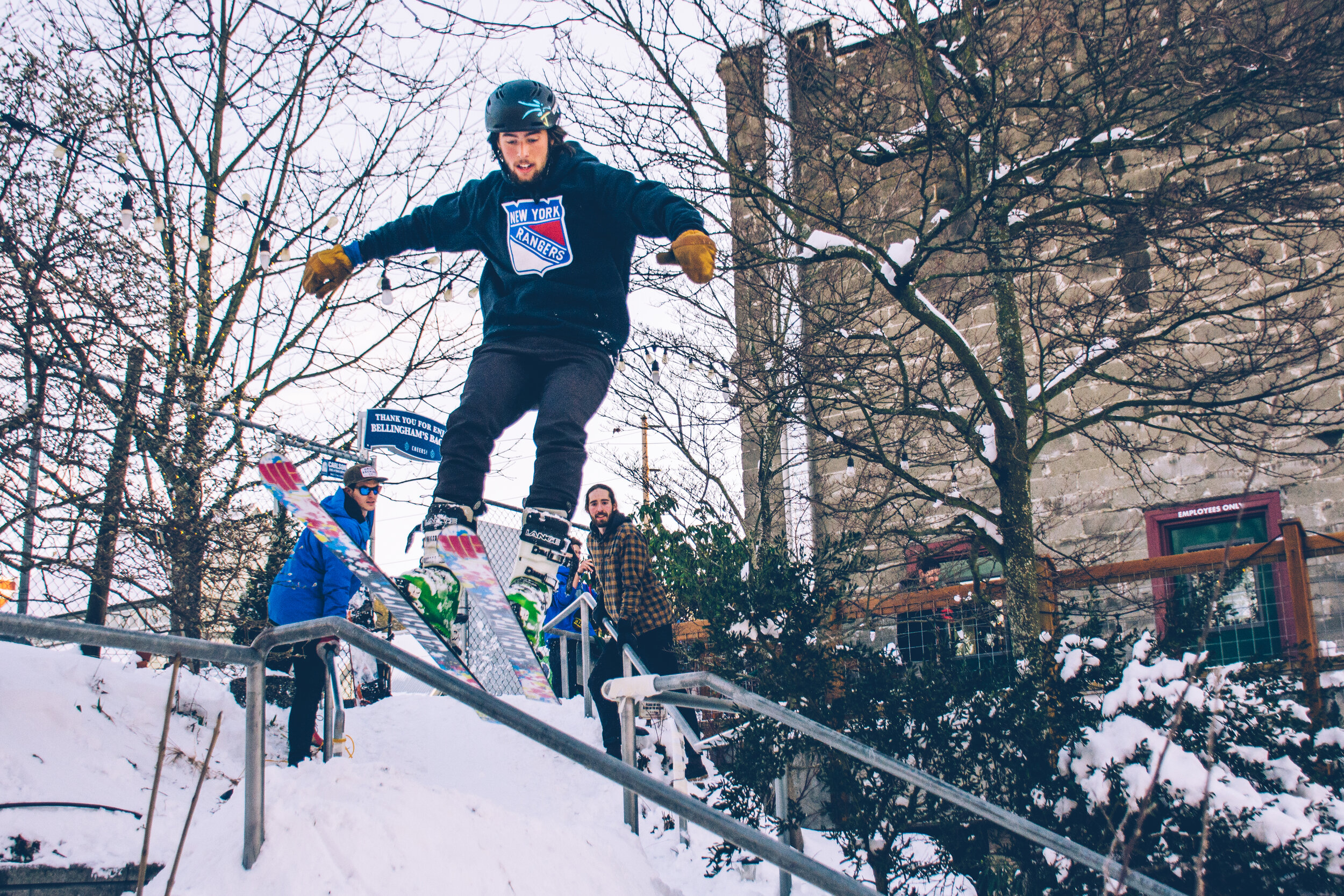 An image of a skier executing a grind on one of the beer garden's handrails on a snow day.