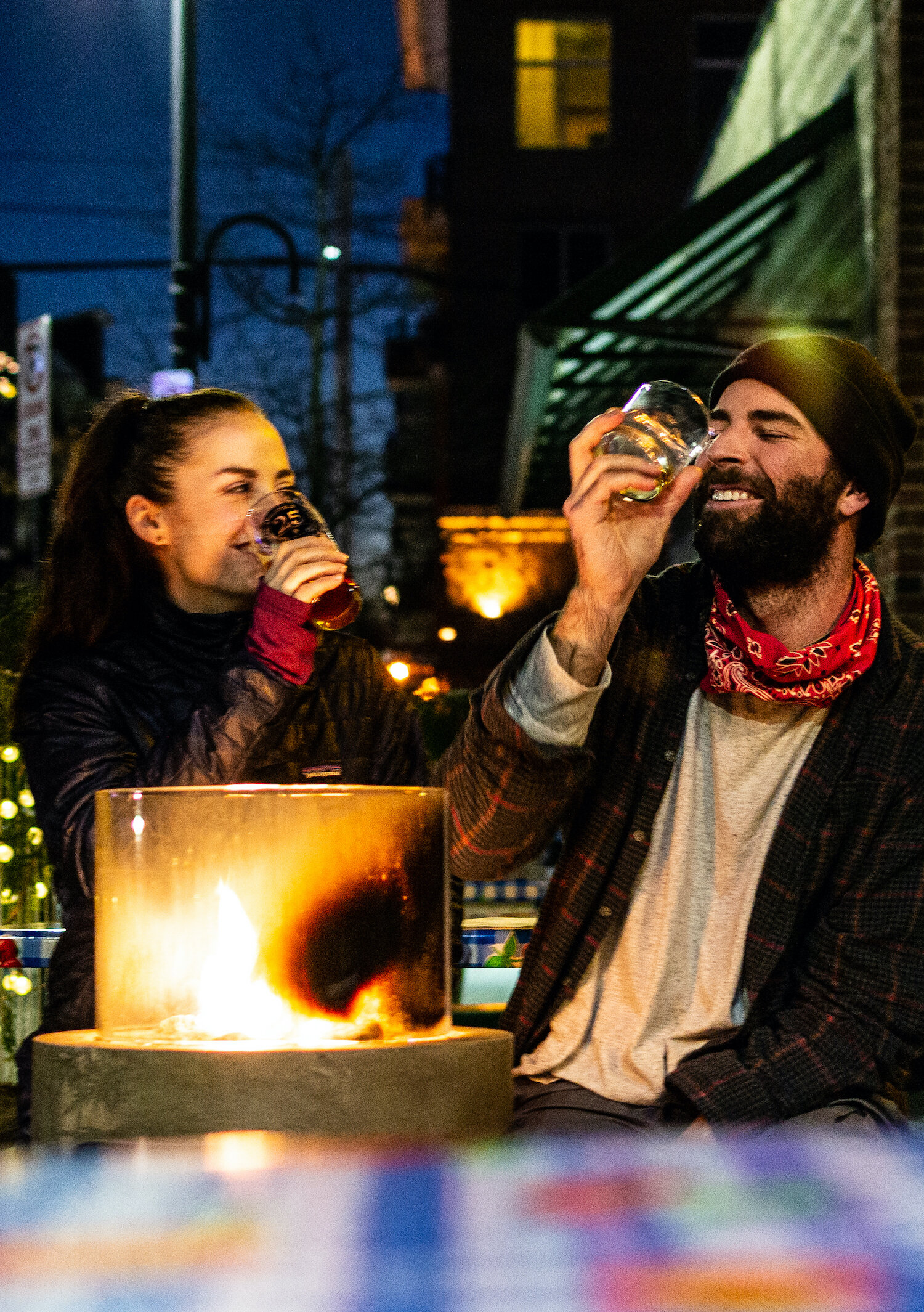 Two guests enjoy drinks by the fire pits available on the Patio for colder fall nights.