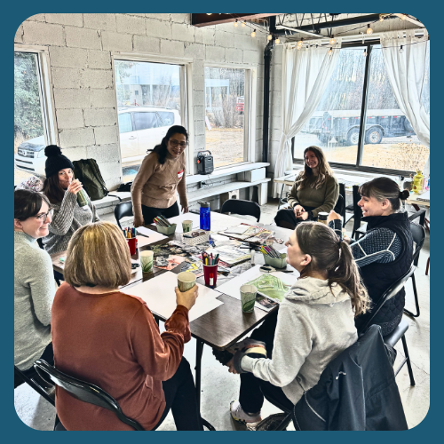 Workshop Participants sit together around a table full of collage supplies