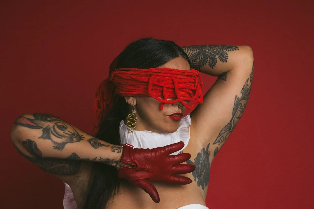 Adriana Rizzolo in a red blindfold and red gloves against a red wall