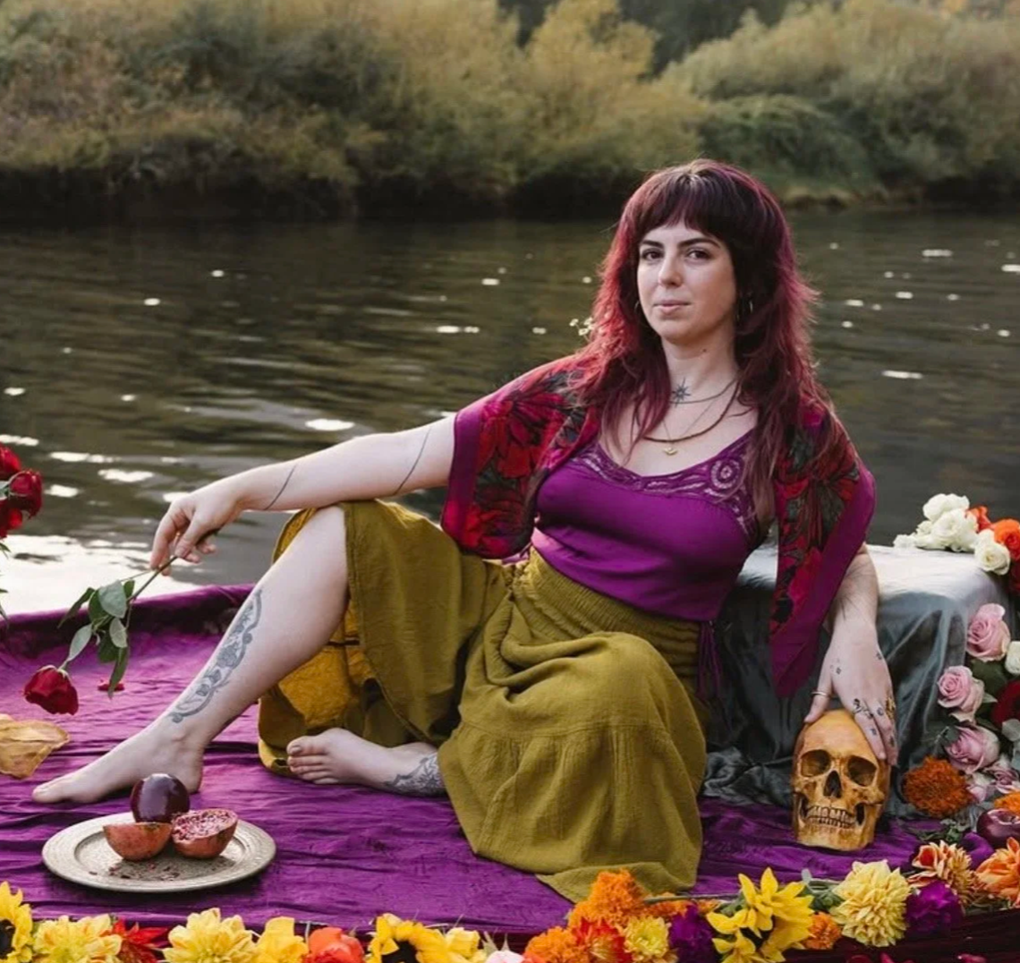 Savanna Wonderwheel seated beside a river with flowers and ritual objects