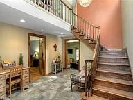 Interior view of a home with a staircase, sitting area, and entryway table.