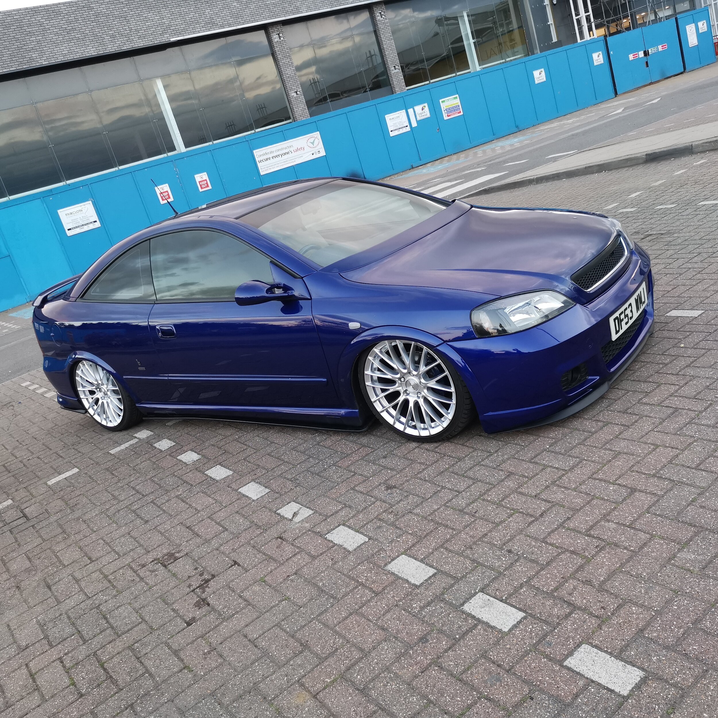 Blue modified Vauxhall Astra 100 edition offside front parked in a carpark.jpg