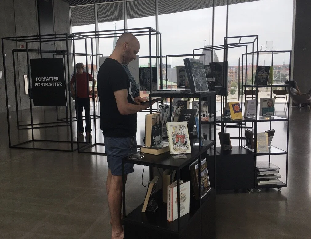 Udstillingsgæst kigger nærmere på litteraturen, der er stillet frem i forbindelse med udstillingen. Der er værker af de syv portrætterede forfattere og bøger om Aarhus. 