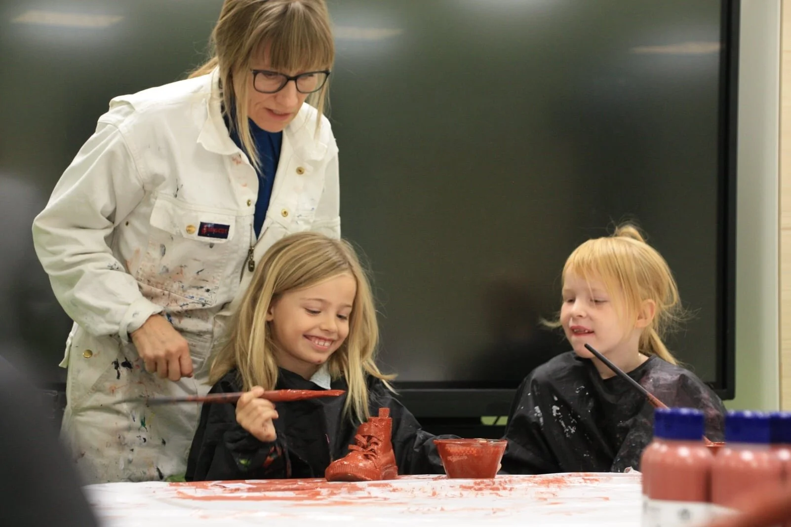 Skotræet, Vestbyen Friskole, Holstebro, 2020.
Elever maler deres aflagte sko på værkstedet - i skolens rustrøde nuance.