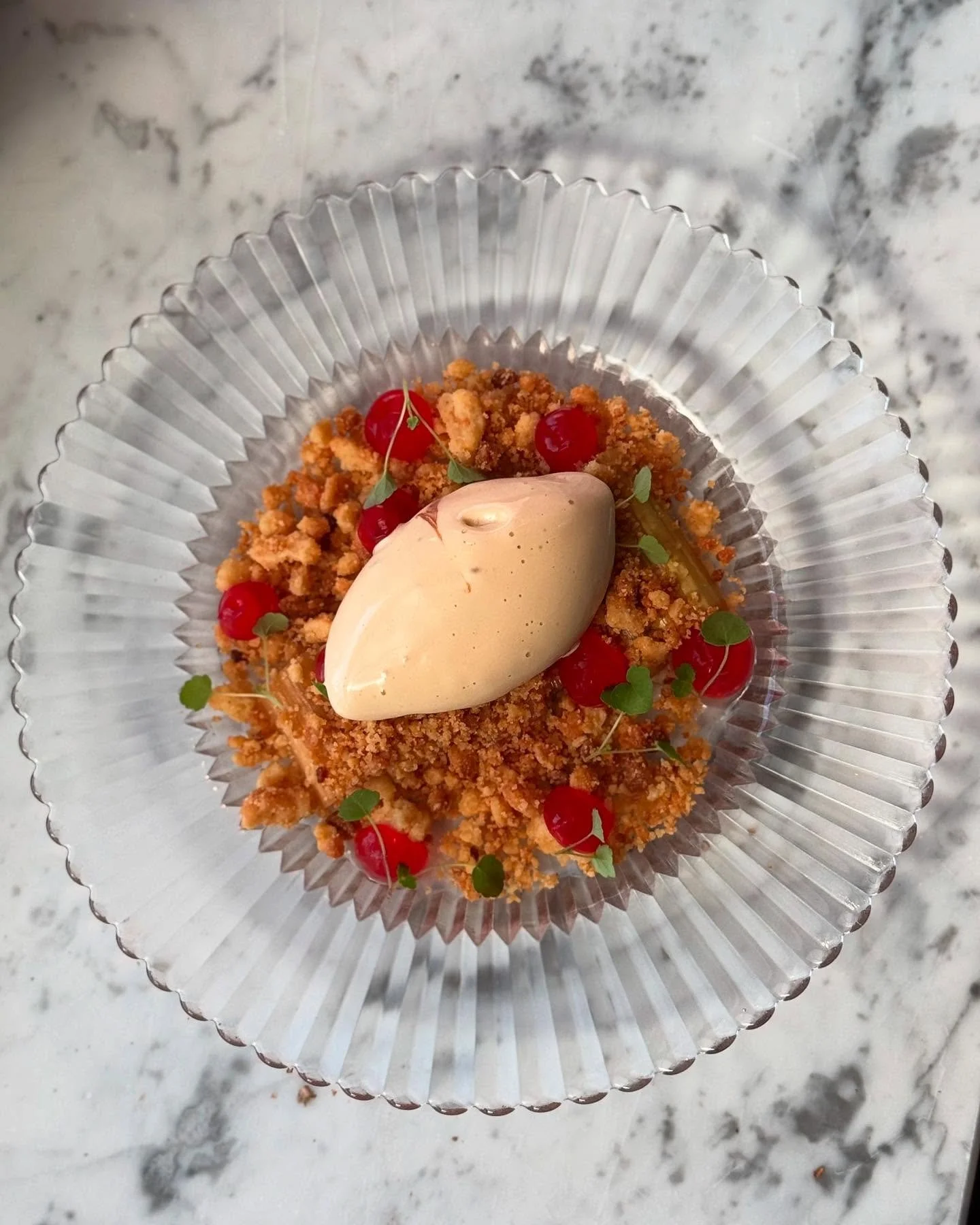 En viskning av v&aring;r p&aring; tallrik.
Inkokt rabarber som dansar med mandelcrumble,
s&ouml;tman fr&aring;n dulcheglass sm&auml;lter som tid i solnedg&aring;ng.
En dessert d&auml;r syra och s&ouml;tma m&ouml;ts i stilla harmoni &ndash;
som om nat