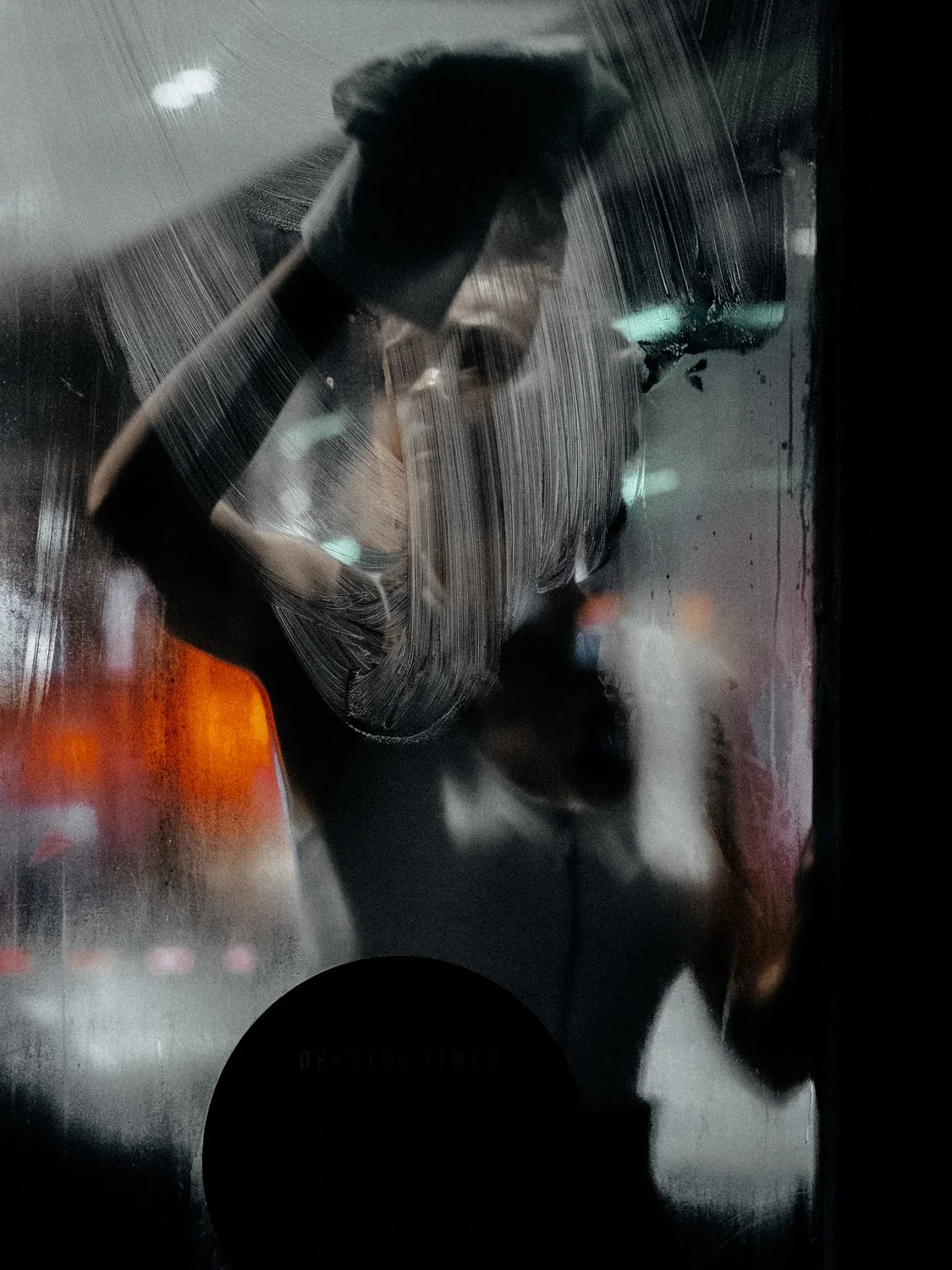 Abstract of a person through streaked glass, night street photography by Joshua K. Jackson.