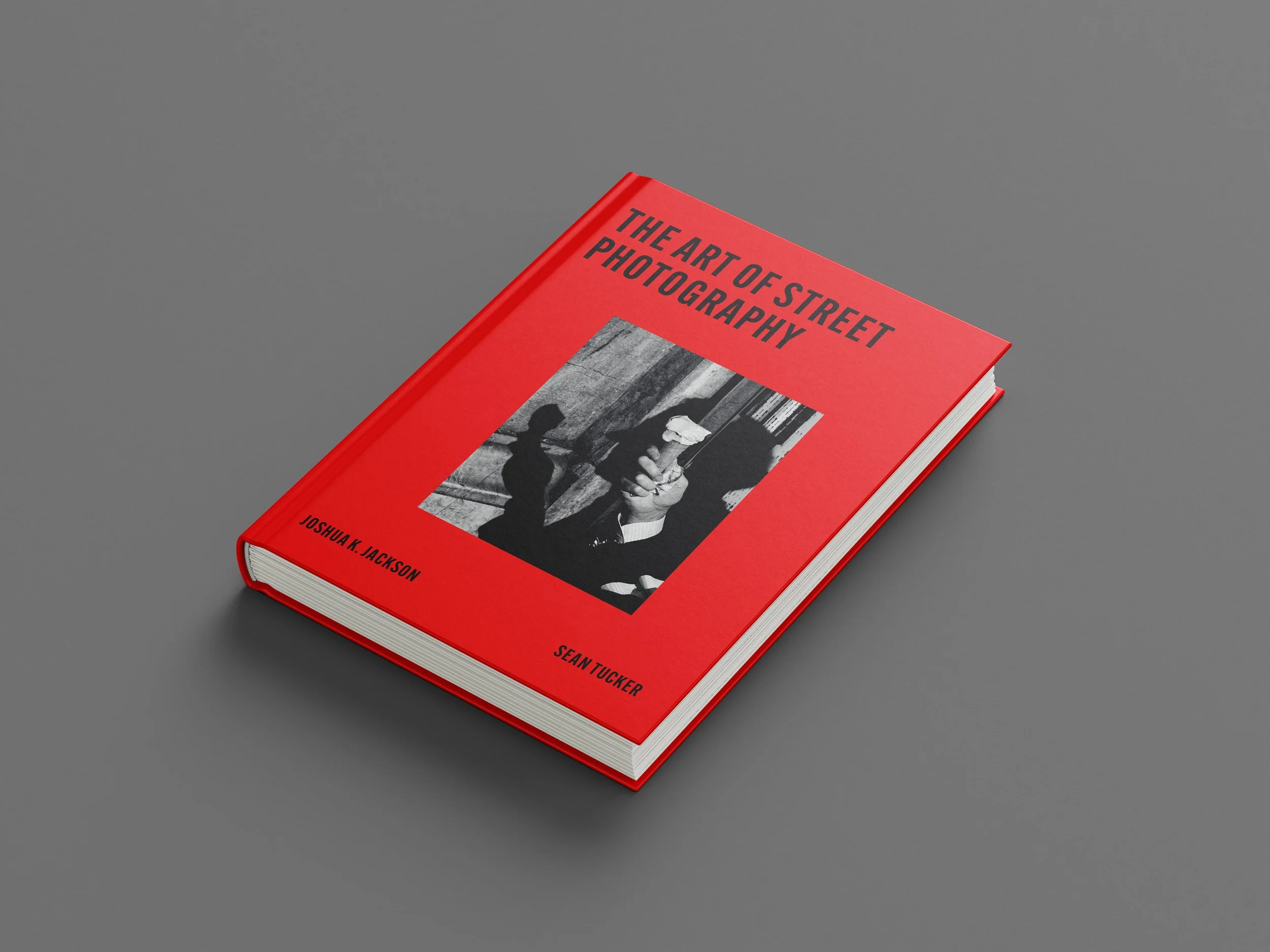 A red book titled "The Art of Street Photography" by Sean Tucker on a gray background.