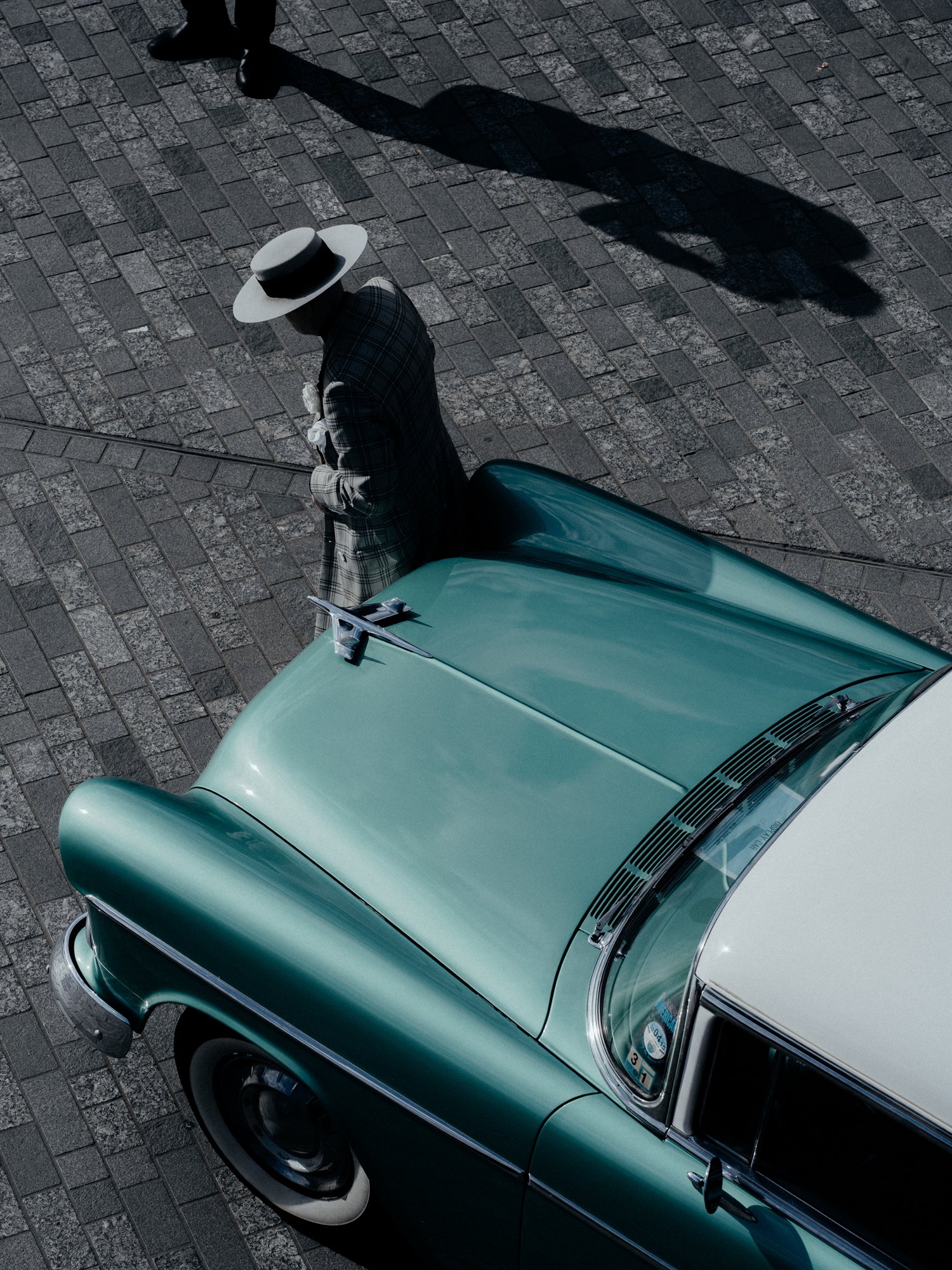 High-angle street photography. A vintage green American car is positioned on a paved street Kings Cross London by Joshua K Jackson.