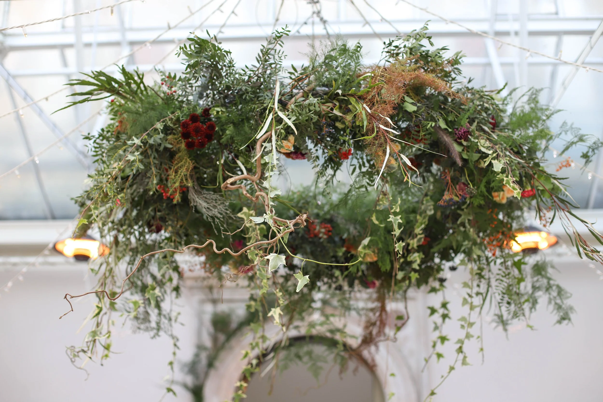 A hanging hoop chandelier arrangement filled with Winter foliage and textures