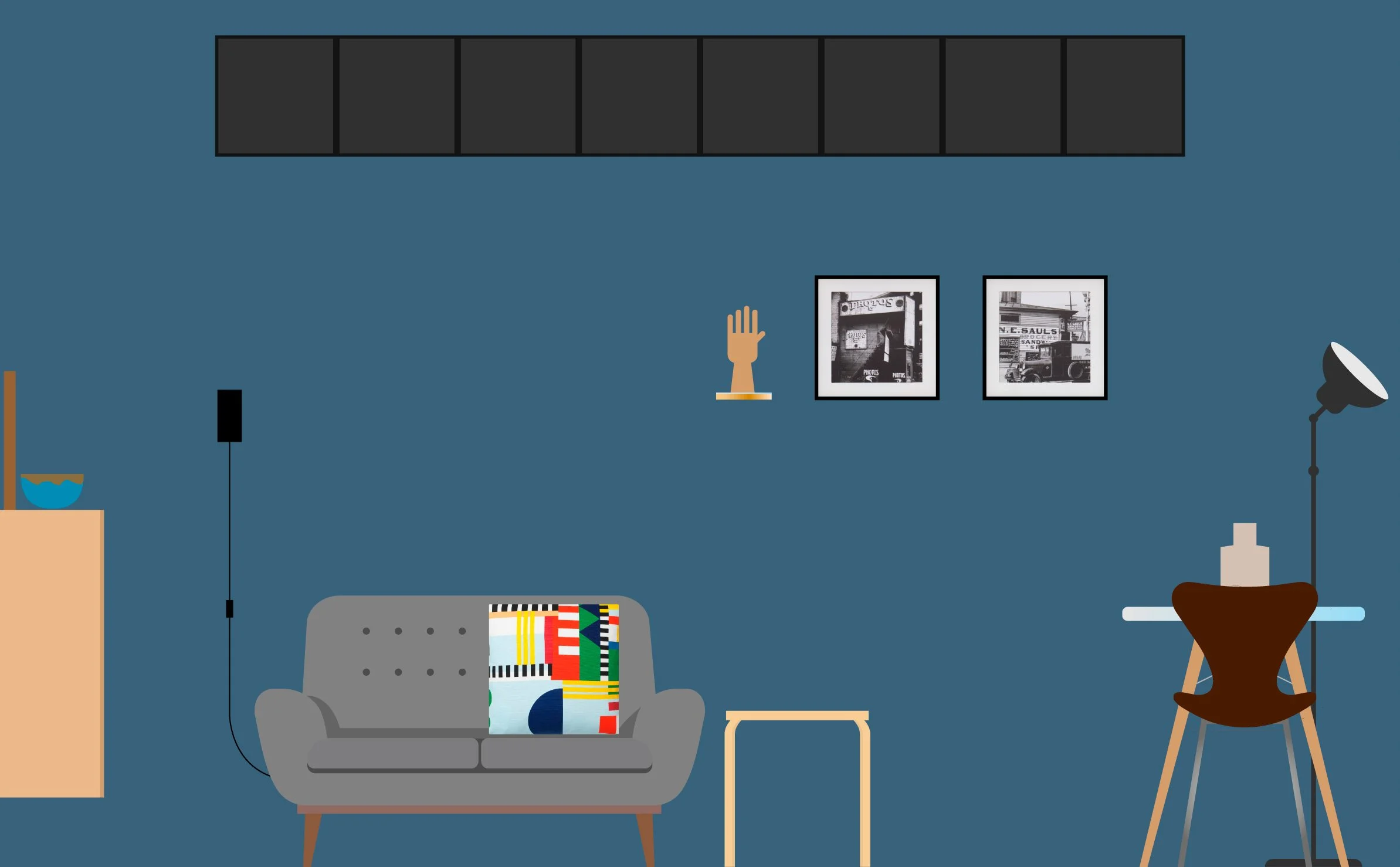 Sala con sofá gris, cojín colorido, mesa auxiliar, estantería con cuenco, dos fotos en la pared, y lámpara de pie negra al lado de un escritorio con silla de madera y maniquí.