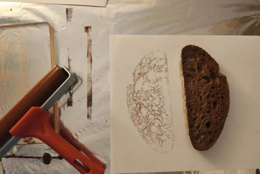 Primer plano de un sello de caucho, un soplete y una hoja con una impresión de la imagen de un pan integral de centeno. Agosto Creative Studio, diseño de tiendas y restaurantes. Retail Design. Branding. Fotografía.