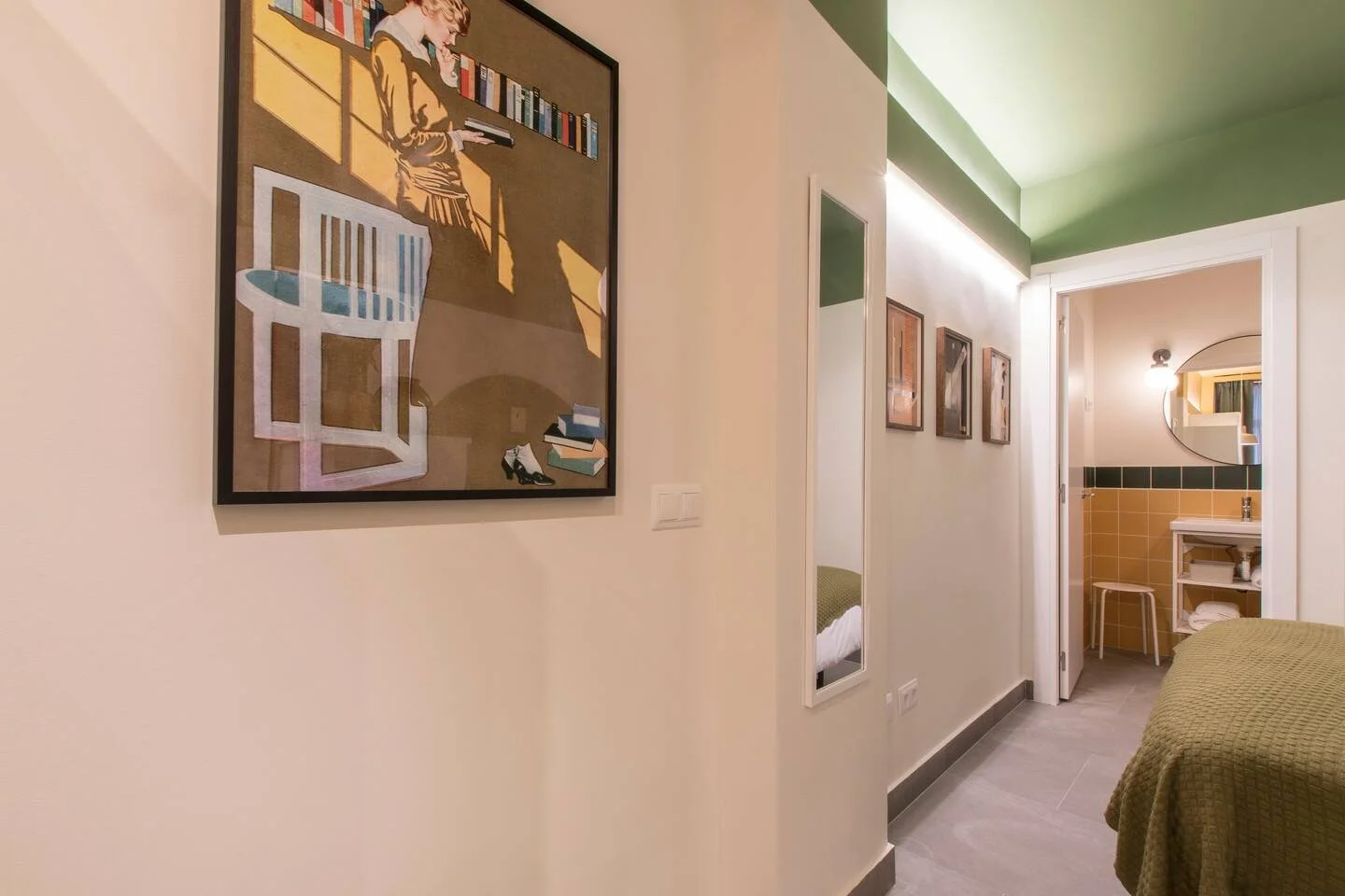 Habitación con cuadro en la pared, espejo, y vista a un baño con lavabo y silla