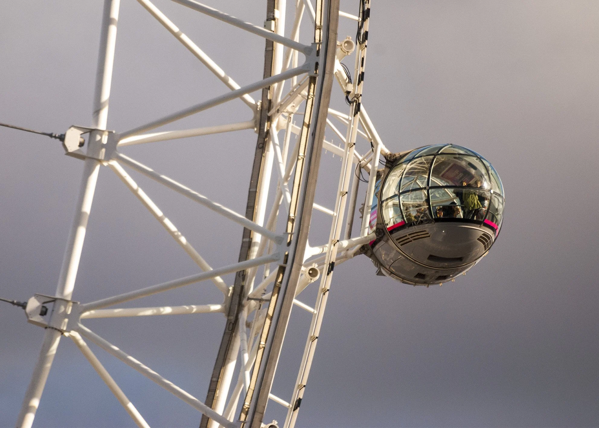 Cabina de una rueda de la fortuna moderna con pasajeros dentro, estructura metálica visible. Fotografía arquitectónica de Londres. London architecture photography. Por Agosto Creative Studio Barcelona. Agencia de diseño y comunicación Barcelona.