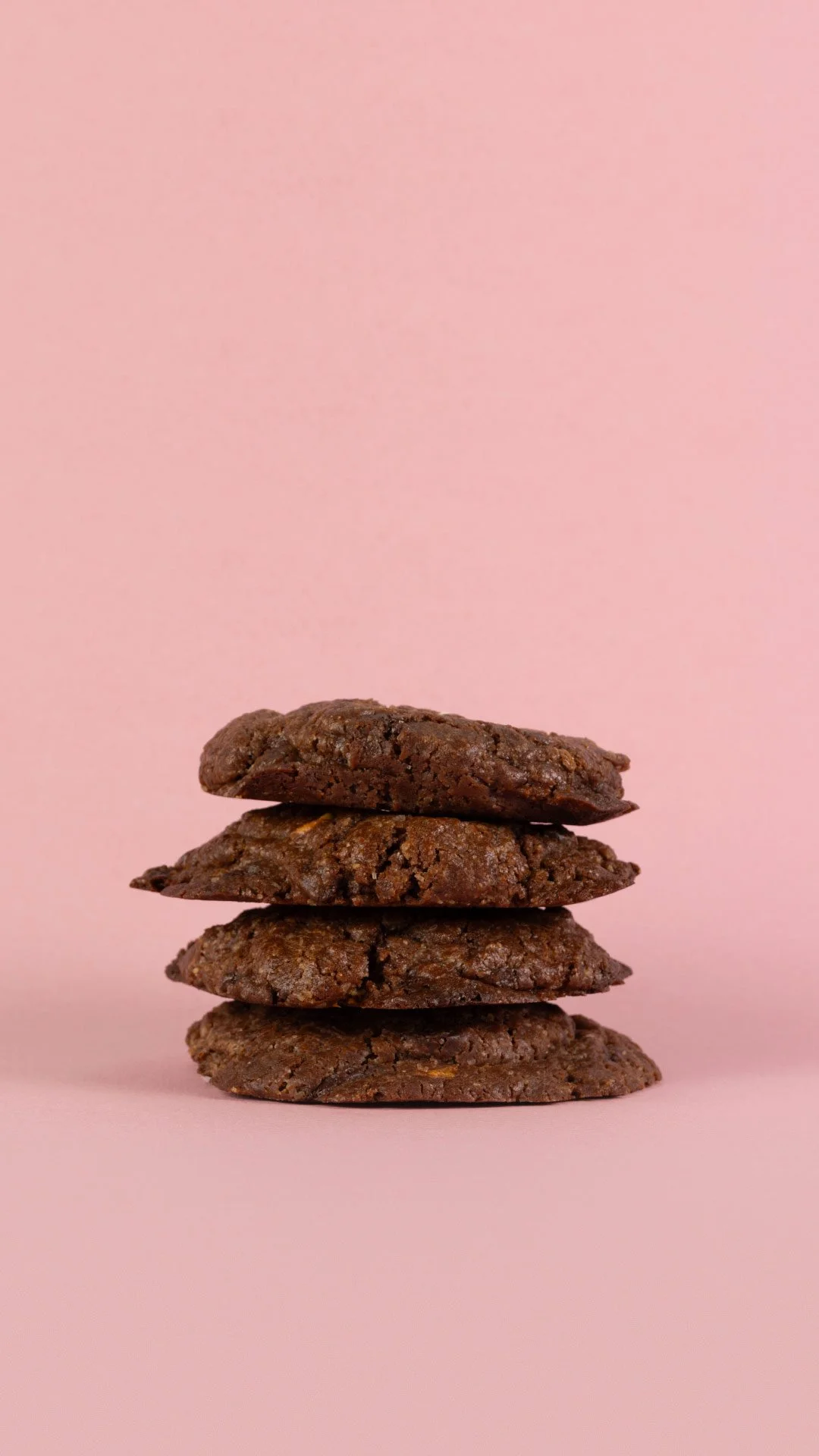 Cuatro galletas de chocolate apiladas sobre un fondo rosa. Mionas Bakery. Especialidad en Cookies en Sitges. Retail Design, diseño de tiendas. Foto de producto.