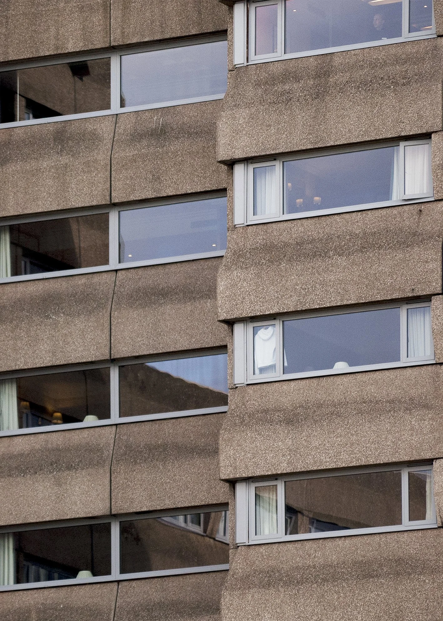 Fachada de edificio con varias ventanas reflectantes en un diseño brutalista. Las ventanas tienen cortinas y objetos visibles en el interior. Fotografía arquitectónica de Londres. London architecture photography. Por Agosto Creative Studio Barcelona.